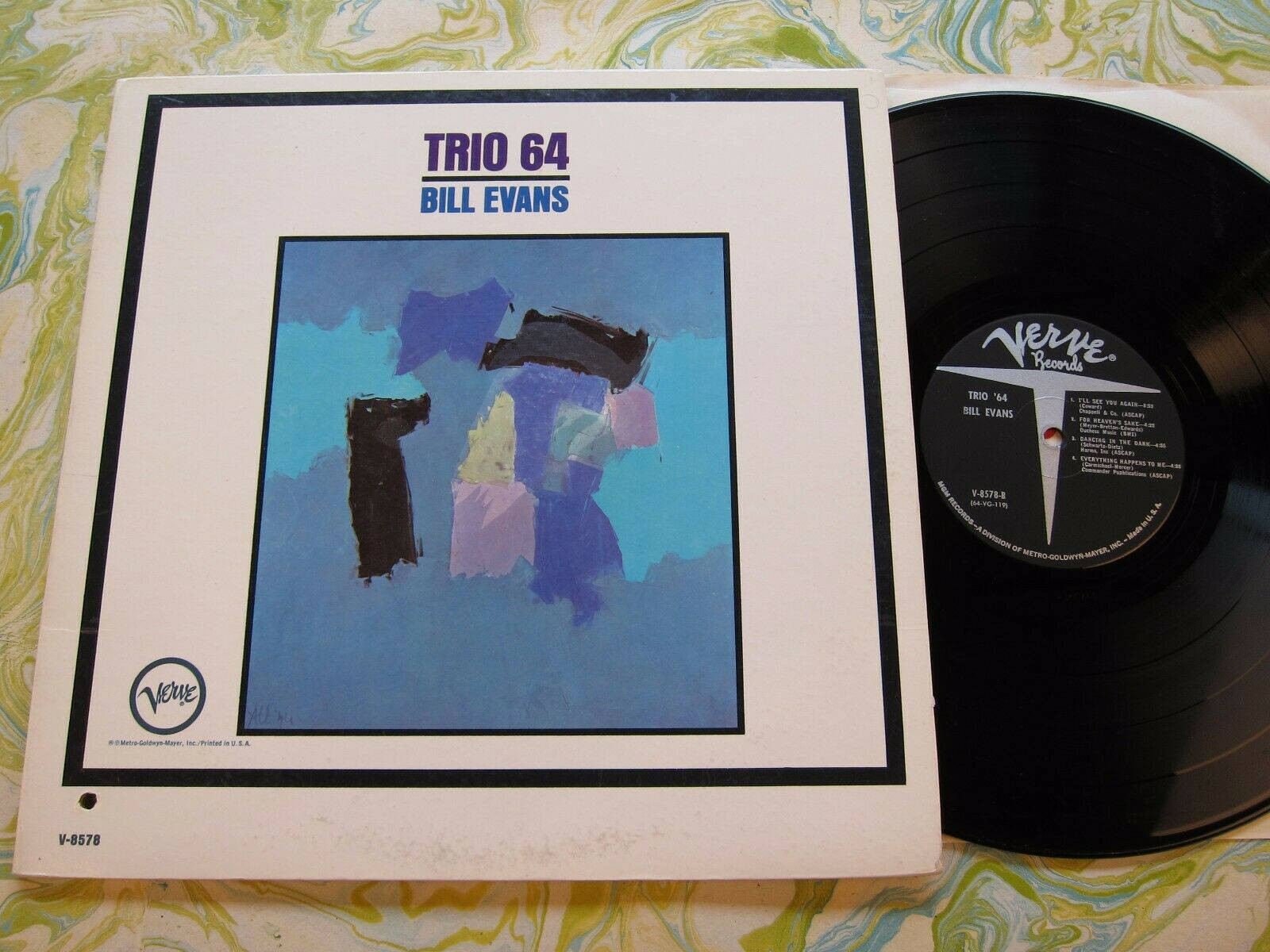 比爾·艾文斯的原聲唱片 壁紙 — 一張復古Bill Evans Trio 64黑膠唱片和專輯封面放在旋轉的綠色和白色圖案布料上。