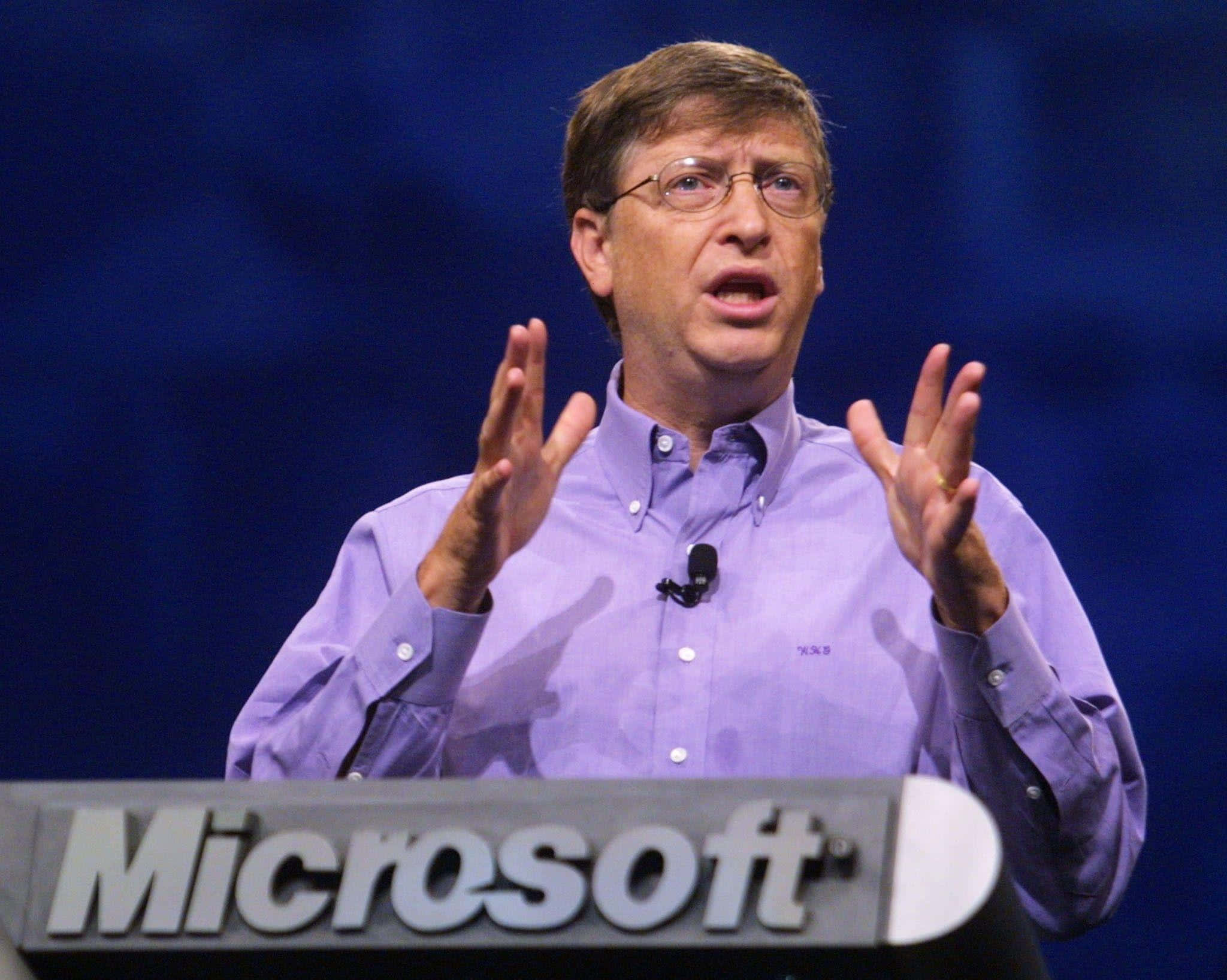 Bill Gates 桌布 壁紙 — 比爾·蓋茨在微軟活動中熱情演講，身穿紫色鈕扣襯衫，背景為藍色。