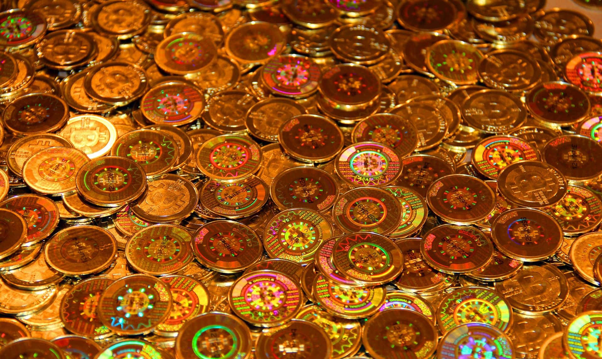 一堆帶有彩色全息設計的金色加密貨幣硬幣。