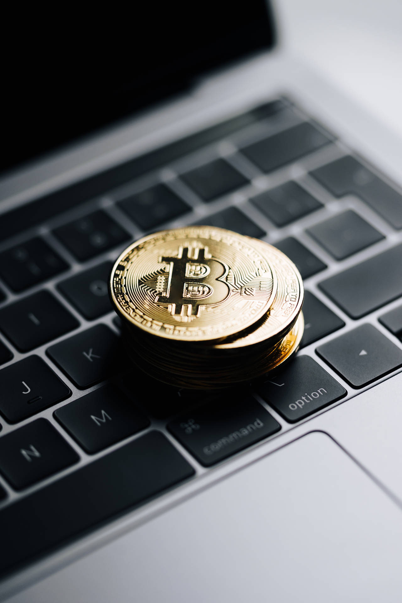 筆記本電腦鍵盤上的一堆金色比特幣硬幣