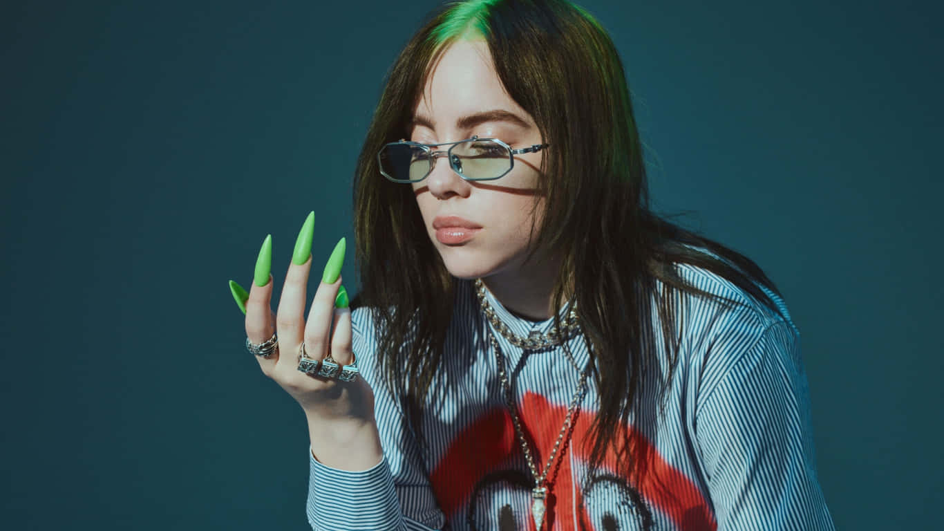Billie Eilish 在攝影棚拍攝中展示綠色指甲和眼鏡。