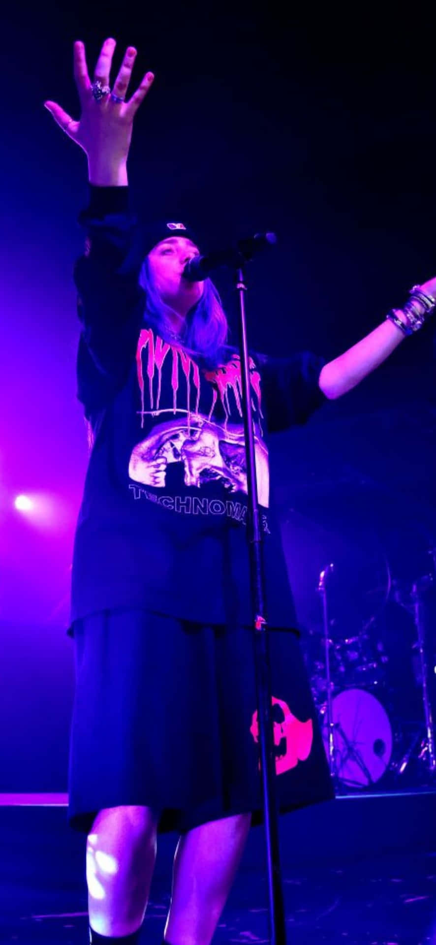 音樂家在紫色燈光下高舉雙臂現場表演。