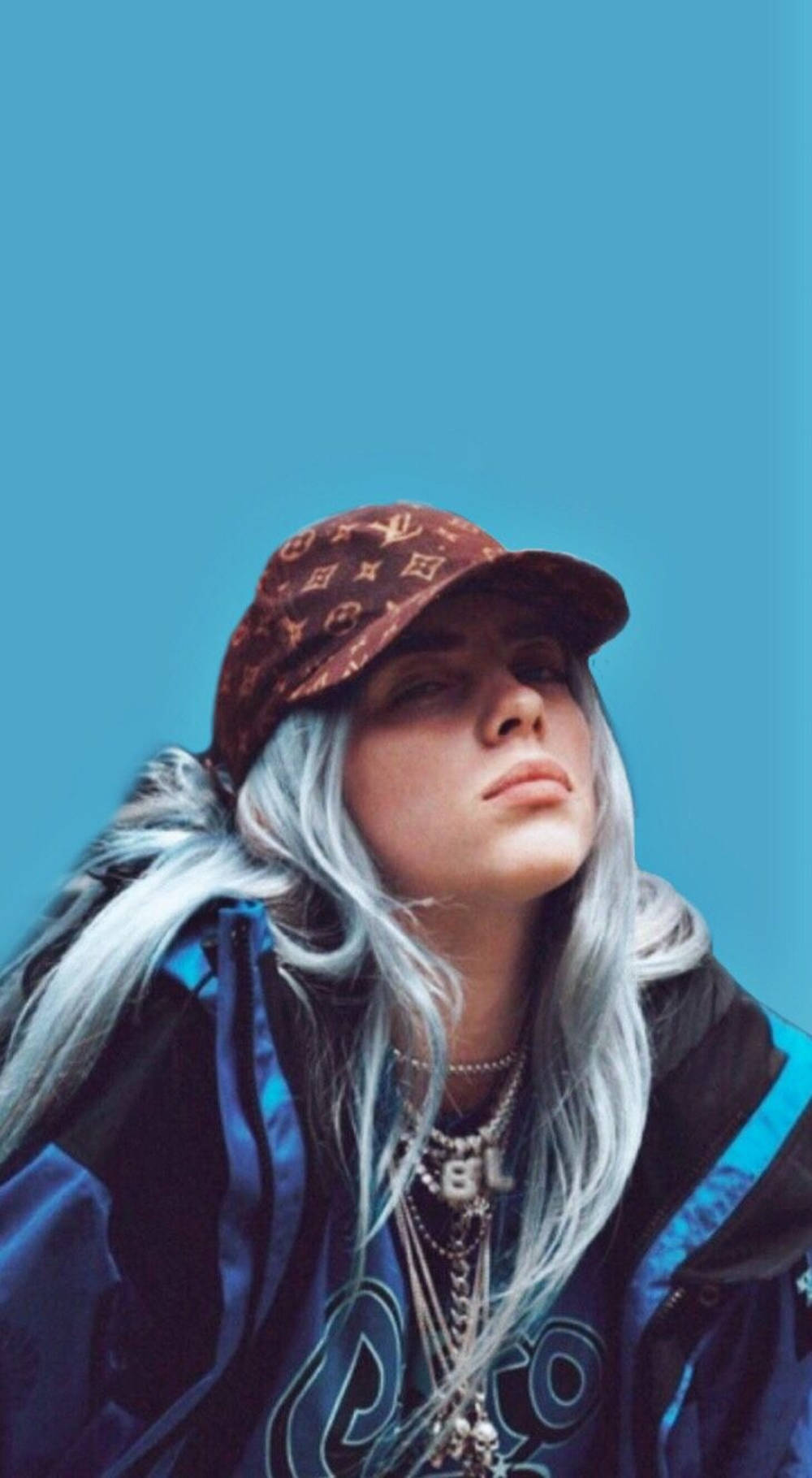 比莉·艾利什藍色美學路易威登帽壁紙 壁紙 — Billie Eilish 抬頭望向一片藍天，戴著圖案帽子和多層項鍊。