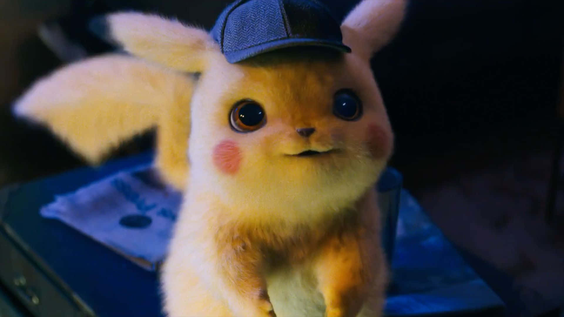 Pokemon Movies 桌布 壁紙 — 毛茸茸的比卡超戴著偵探帽，在昏暗燈光下睜大好奇的眼睛的特寫。