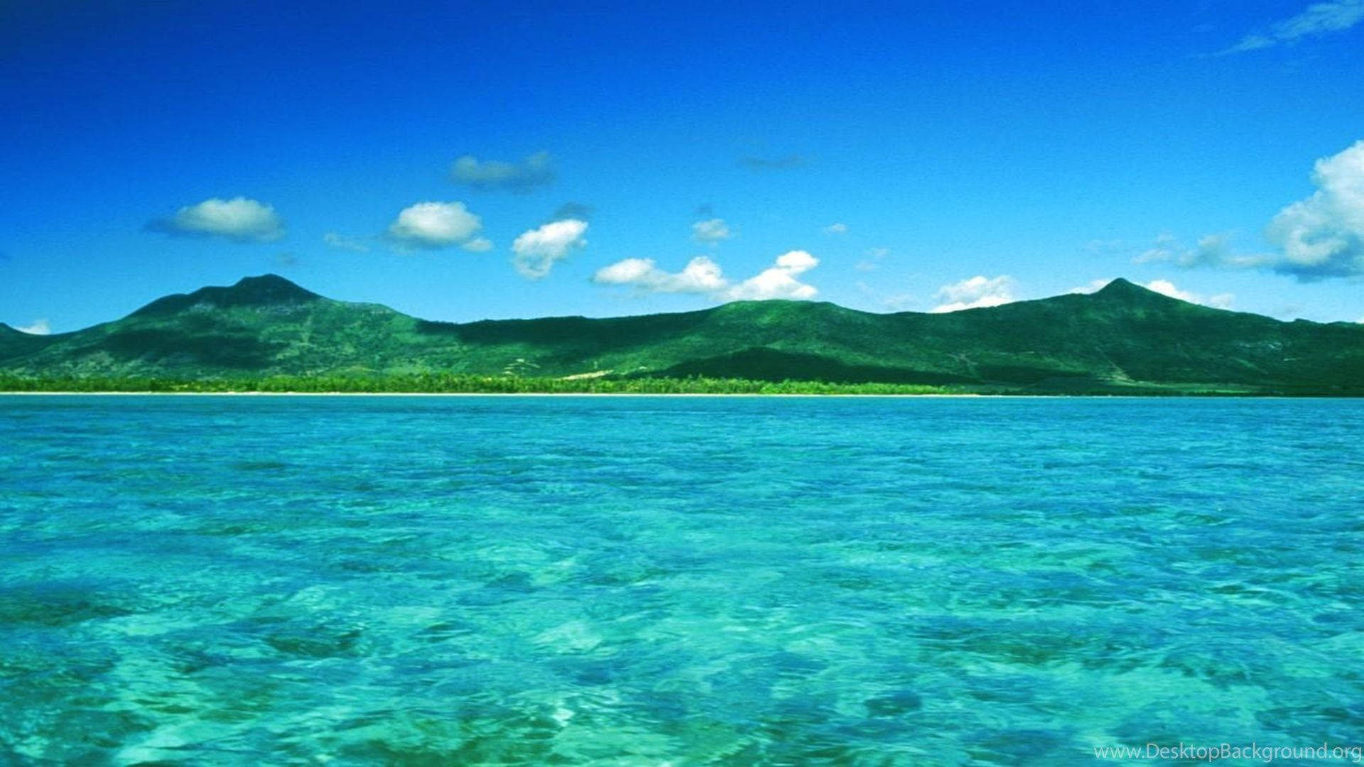 毛里求斯藍海與山脈 壁紙 — 清澈的碧綠海水延伸至鬱鬱蔥蔥的青山，天空湛藍，白雲點綴。