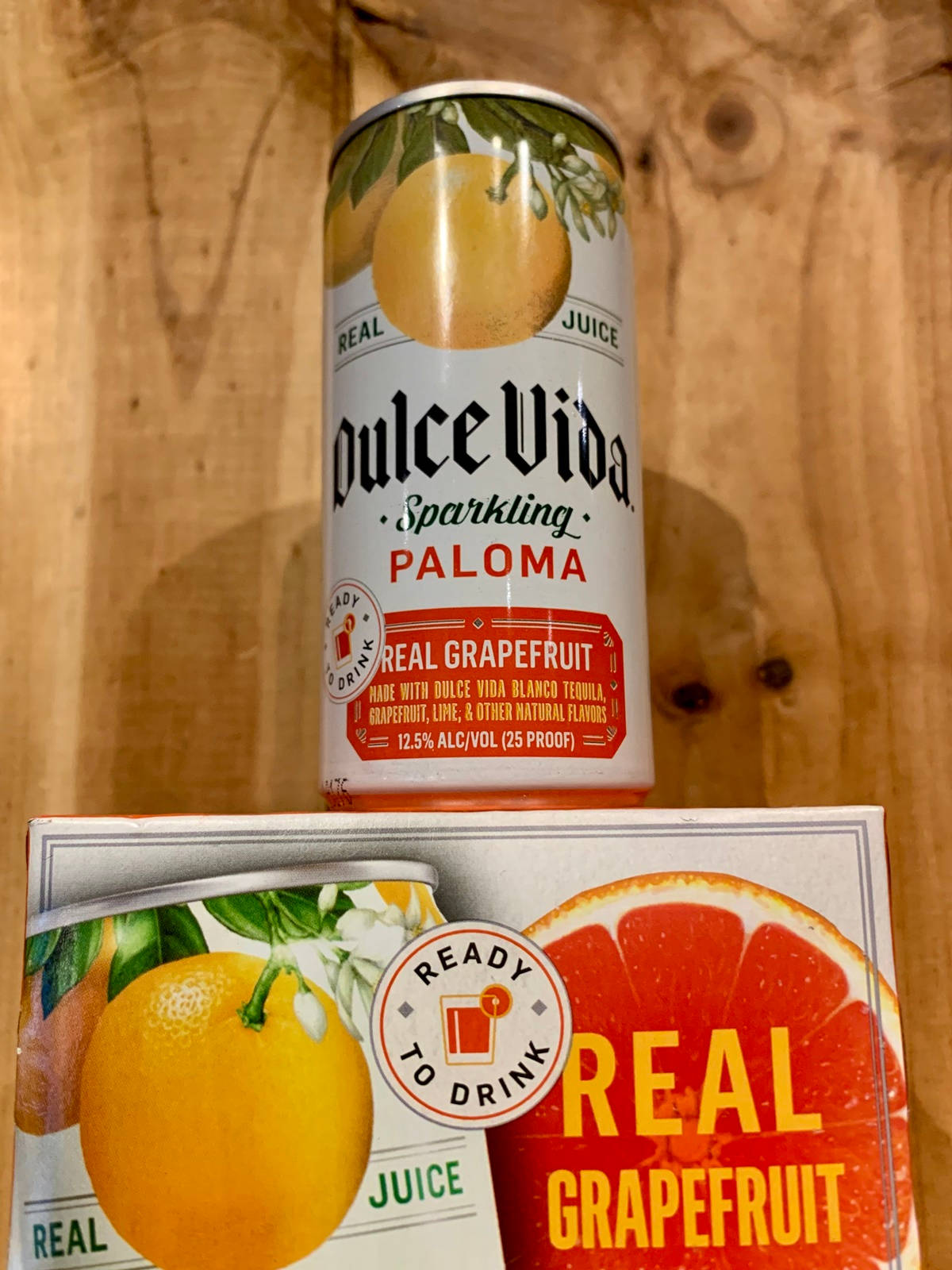 一罐和一盒西柚味即飲氣泡帕洛瑪在木頭上。