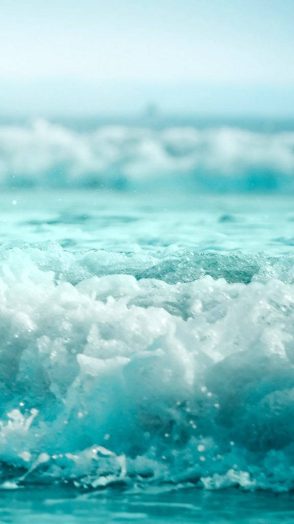氣泡海水自然 iPhone 背景 壁紙 — 在柔和日光下，綠松石色海浪拍打著白色泡沫的特寫。