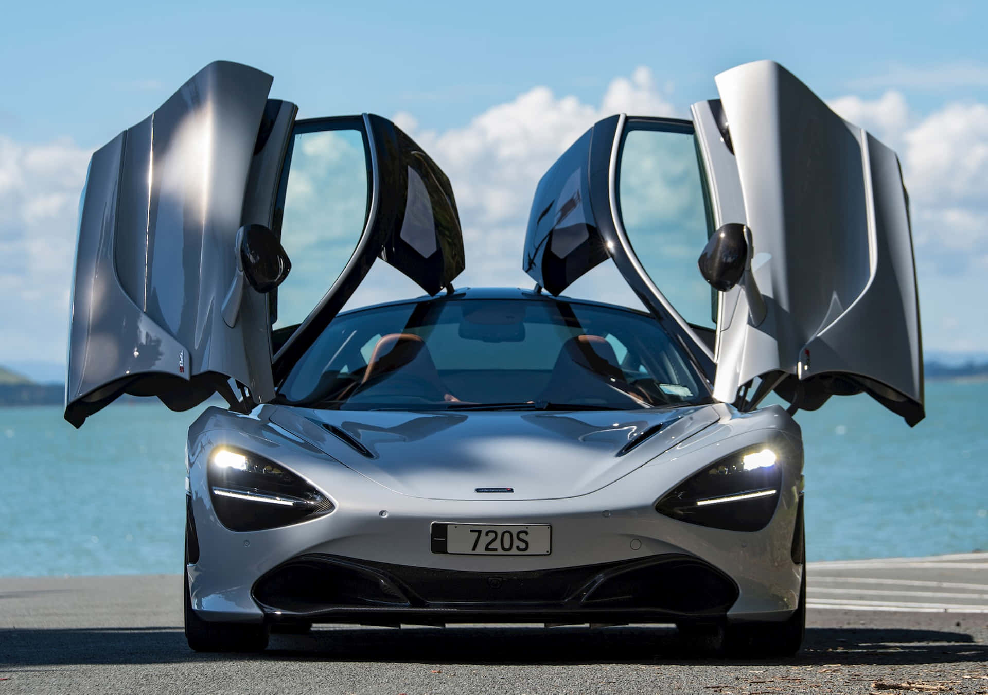 銀色McLaren 720S，鷗翼車門打開，停在海邊。