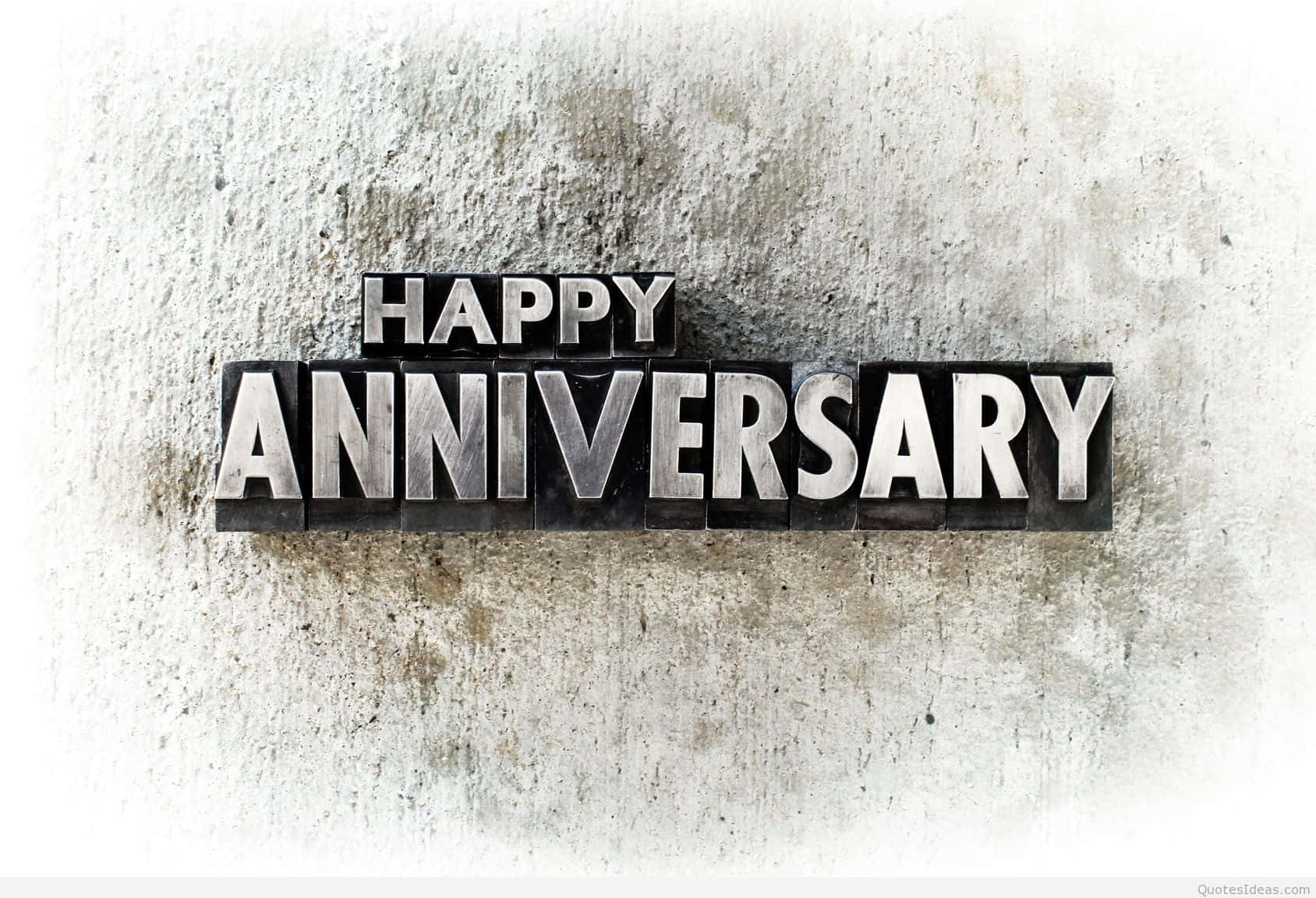 金屬活字塊在混凝土牆上拼出 happy anniversary。