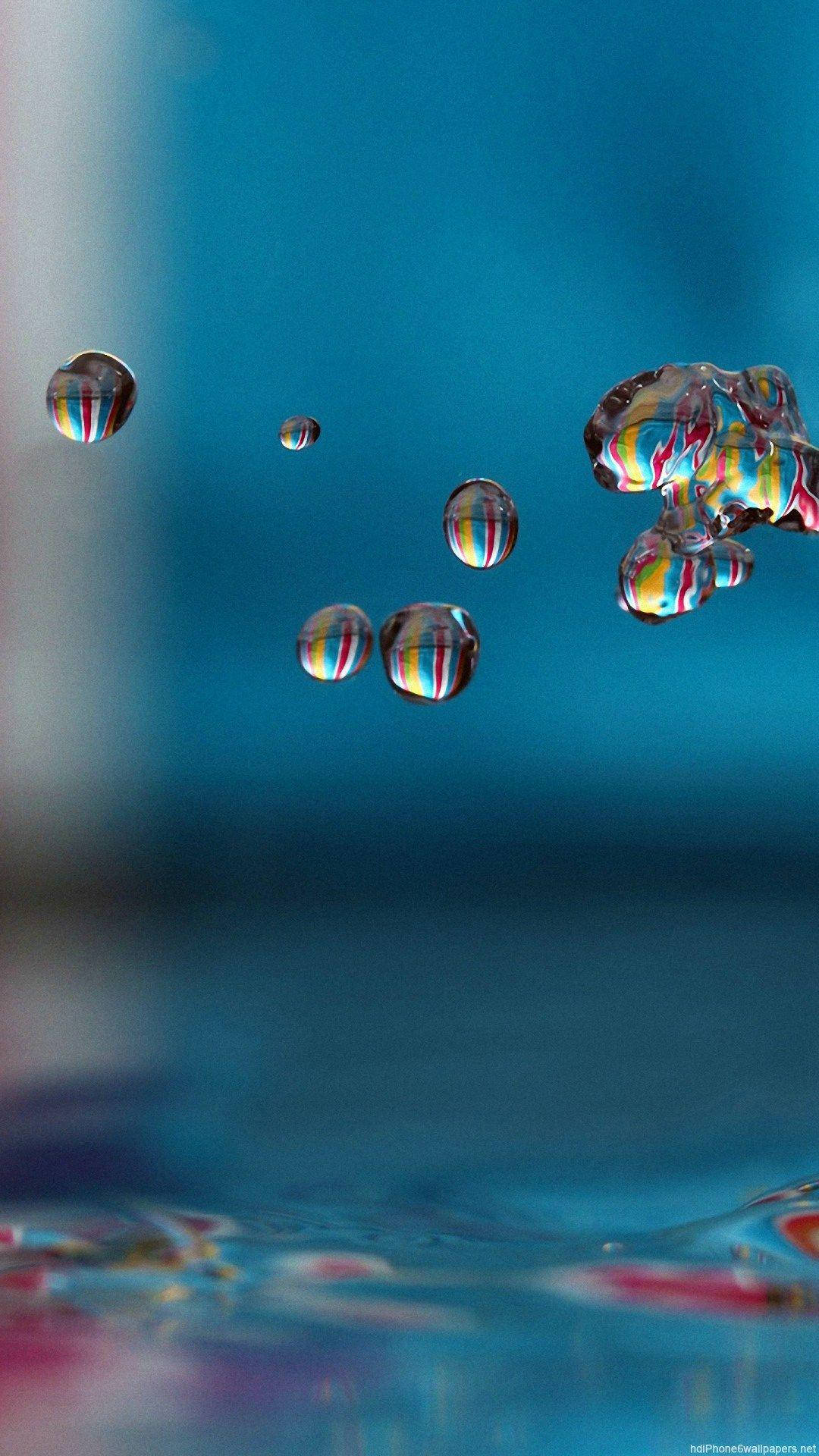 水滴 iPhone 動態壁紙 壁紙 — 懸浮在空中的閃亮水滴在深藍色漸變背景上反射出鮮豔的彩虹色調。
