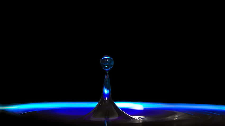 在黑色背景上，懸浮在發光藍色液體表面上方的藍色水滴皇冠。