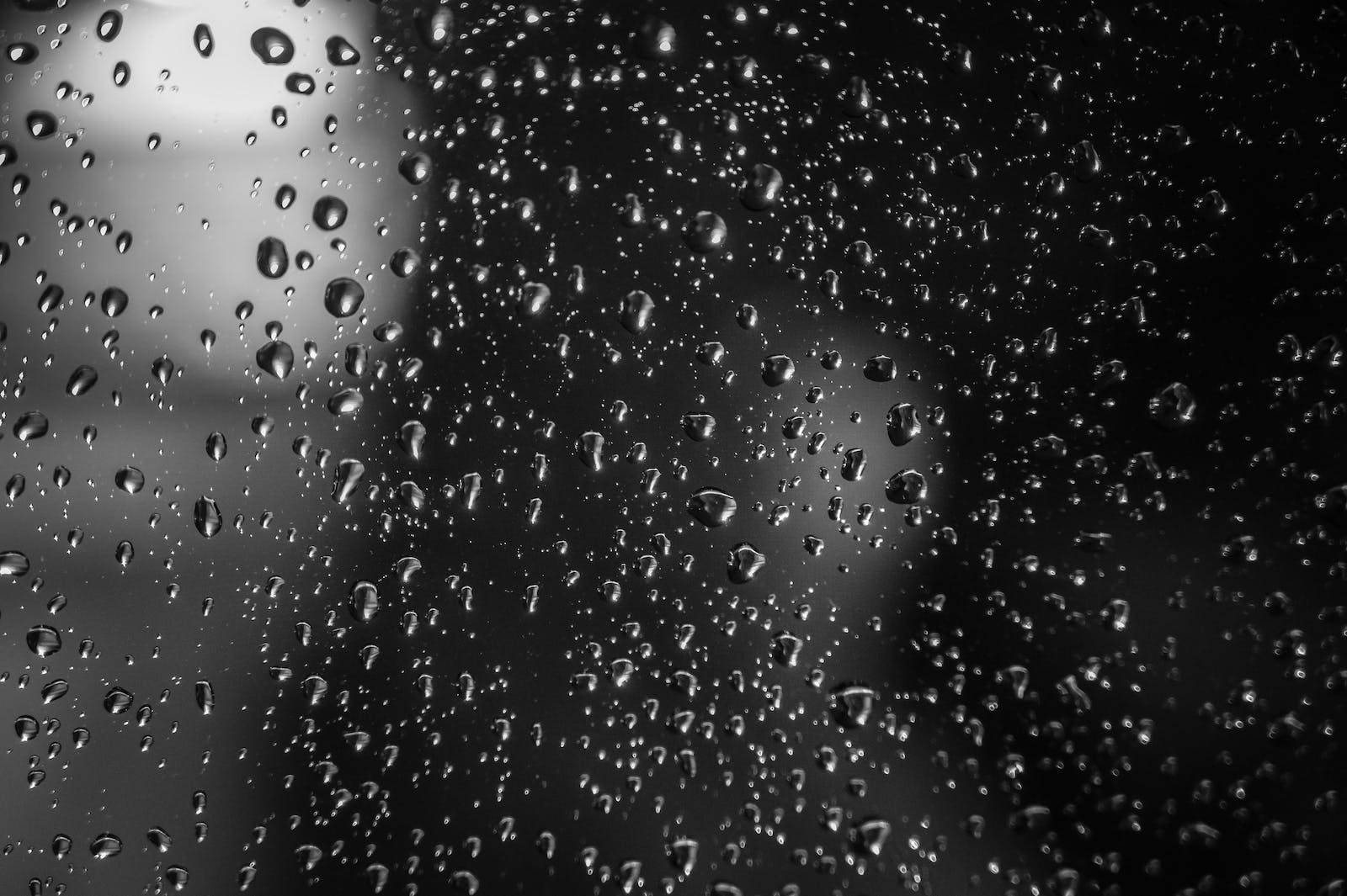 水滴模糊街道 壁紙 — 雨滴依附在玻璃表面，形成帶紋理的單色抽象圖案，背景柔和模糊。