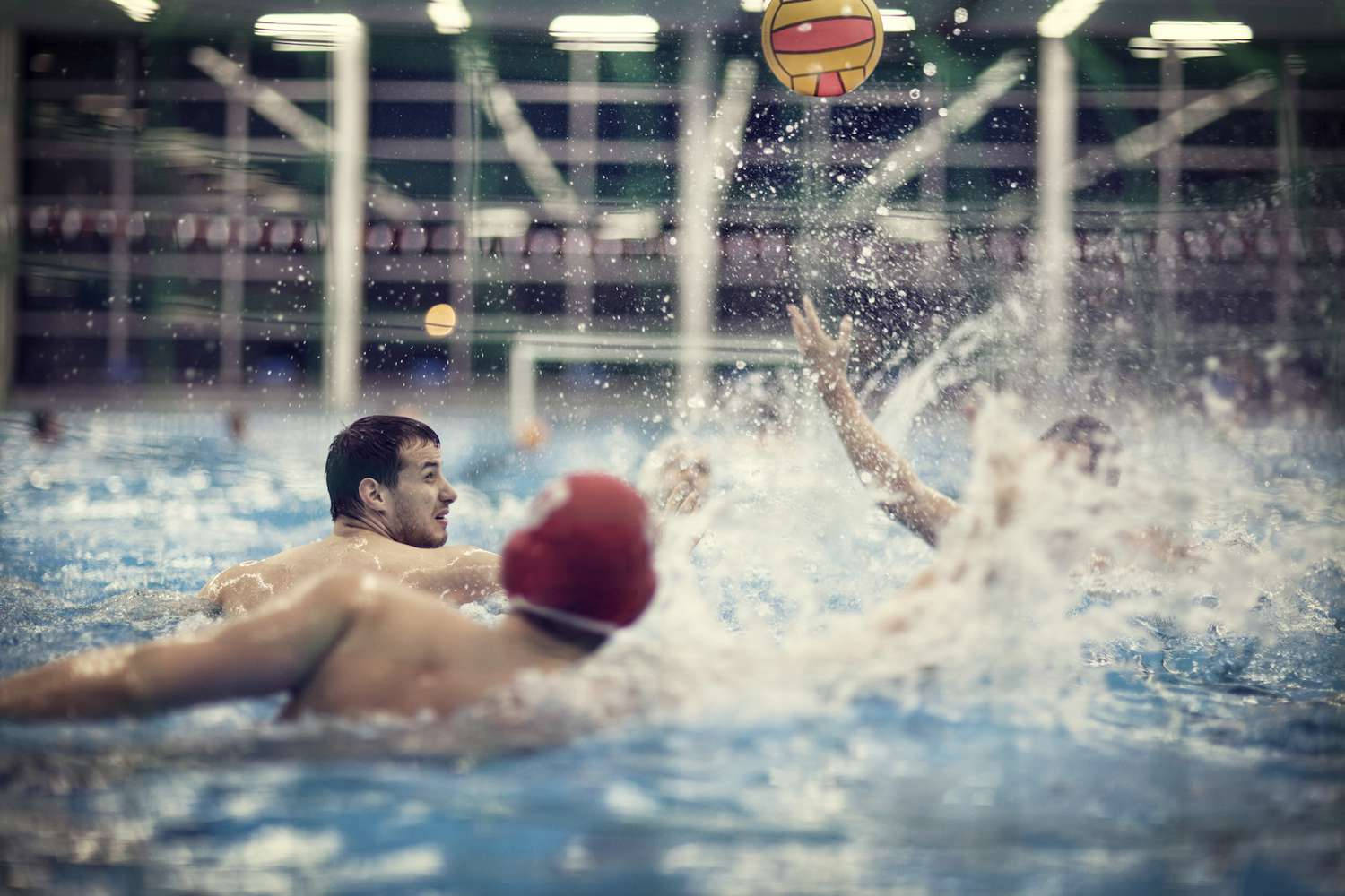兩名男性水球運動員在室內游泳池比賽中行動。