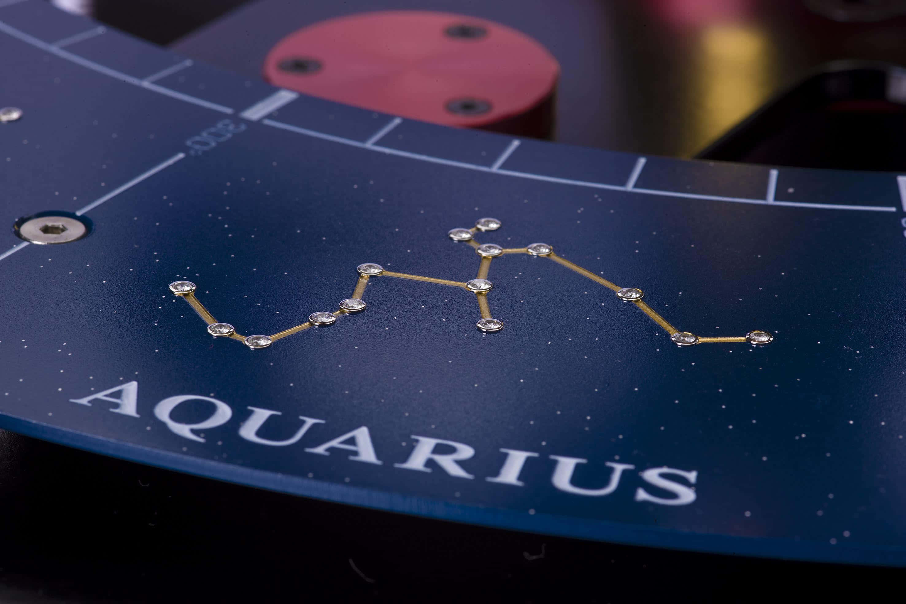 aquarius 桌布 壁紙 — 水瓶座星座近距離特寫，以金色蝕刻在深藍色星空表面上，帶有白色字樣。