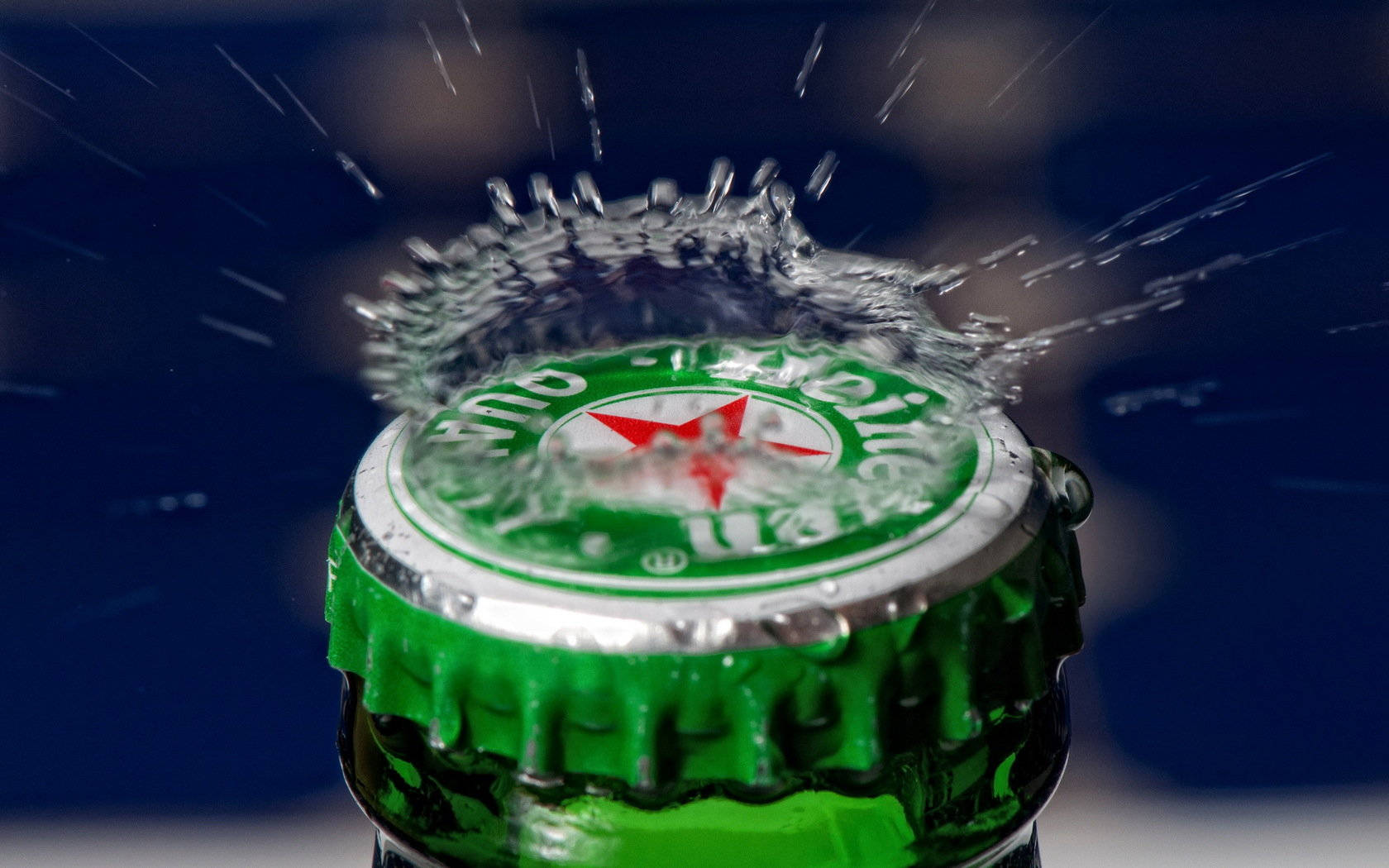 一個綠色啤酒樽蓋彈開，水向外飛濺。