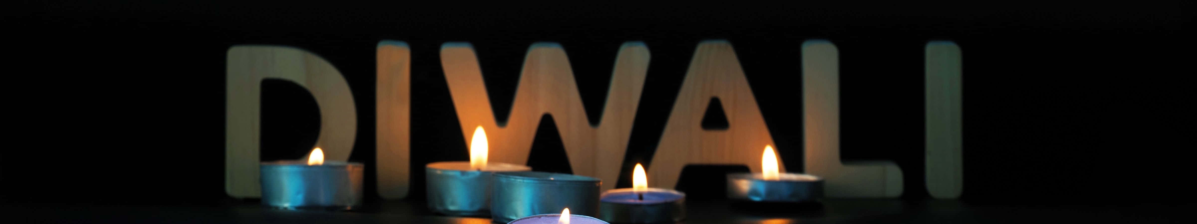 五盞點燃的茶蠟燭在木製DIWALI字母前溫暖地發光。