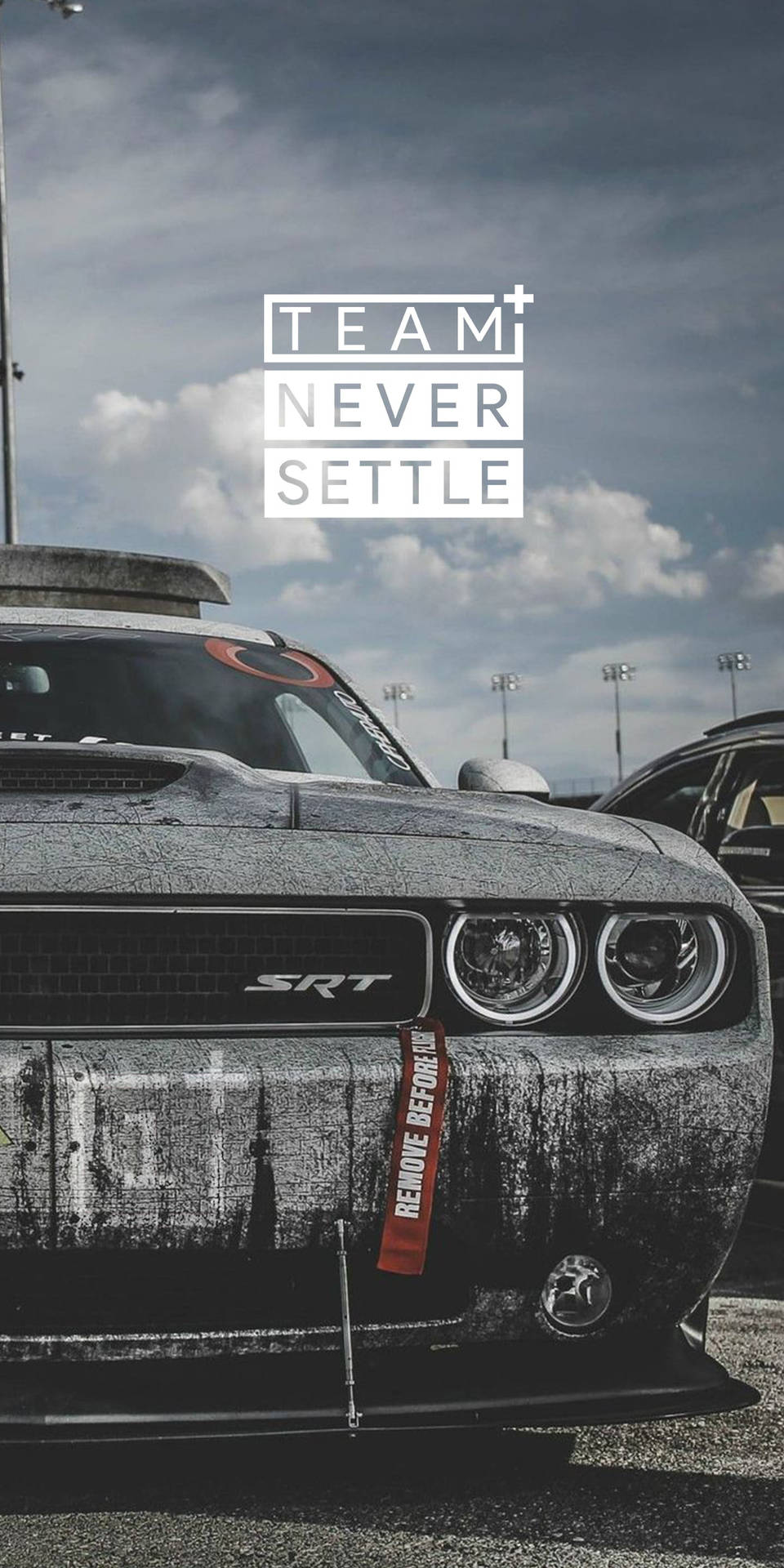 風化黑色道奇挑戰者SRT在賽車場上，帶有「TEAM NEVER SETTLE」字樣。