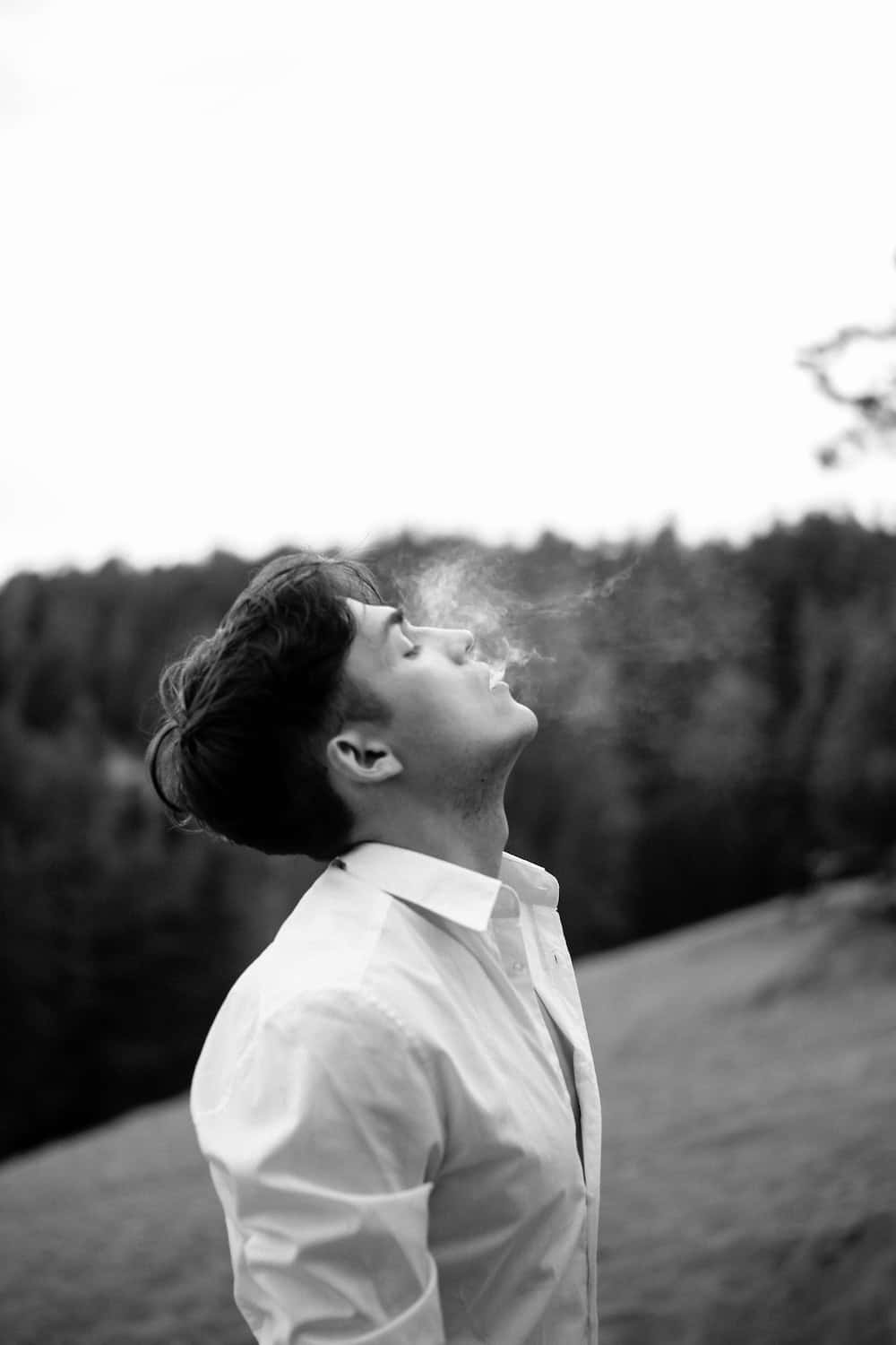男人在戶外黑白背景下呼出煙霧