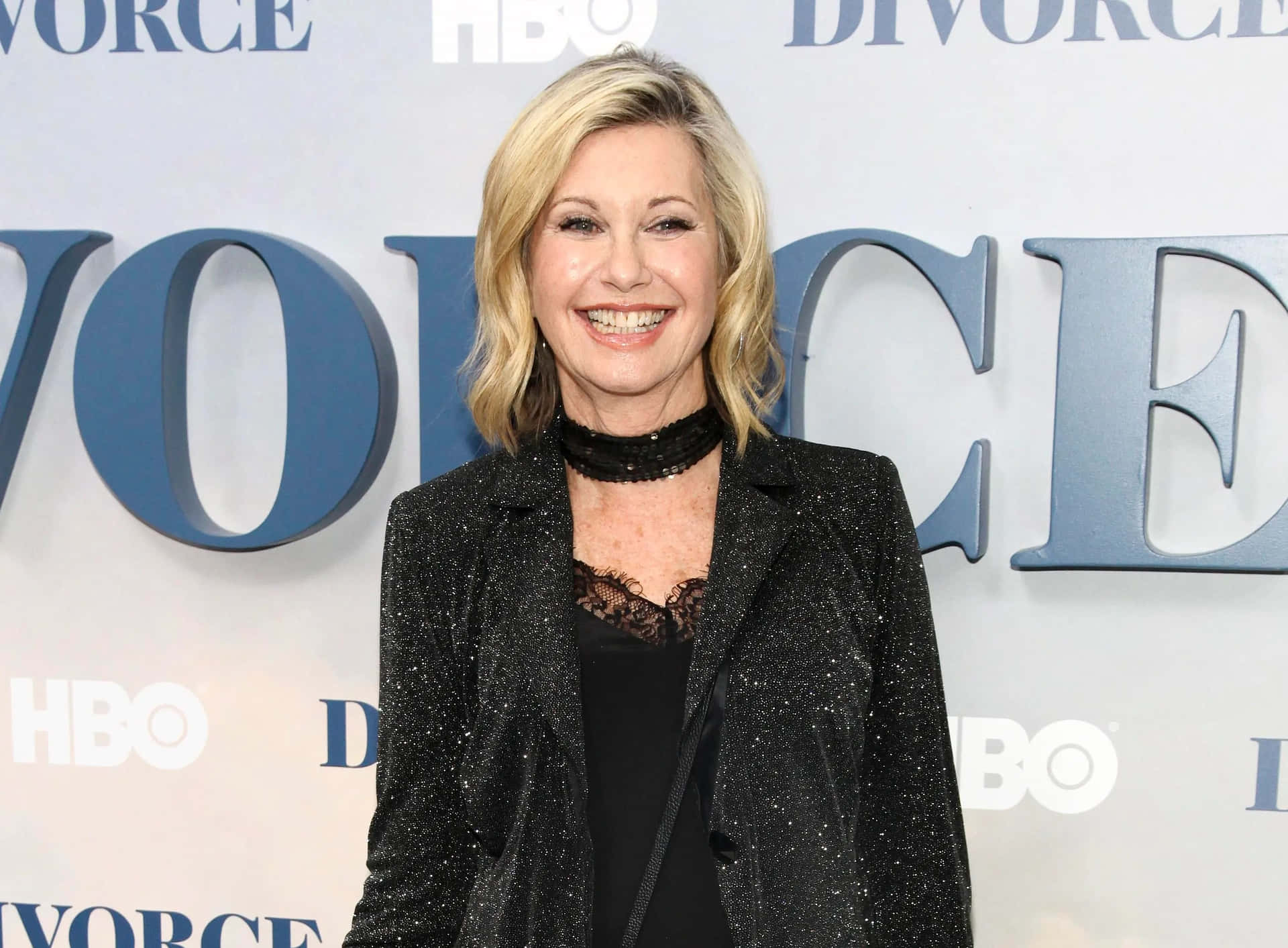 金髮女性穿著閃亮黑色西裝外套在HBO Divorce活動中微笑。