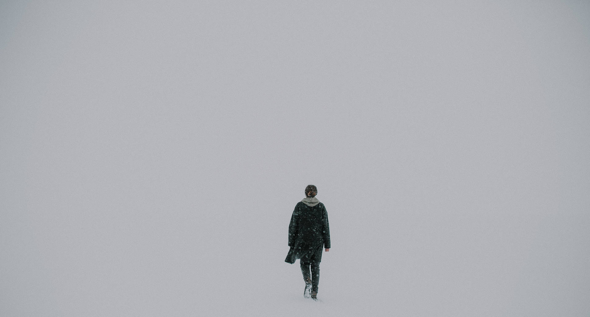 一個人在灰色的冬日獨自走在雪地上。