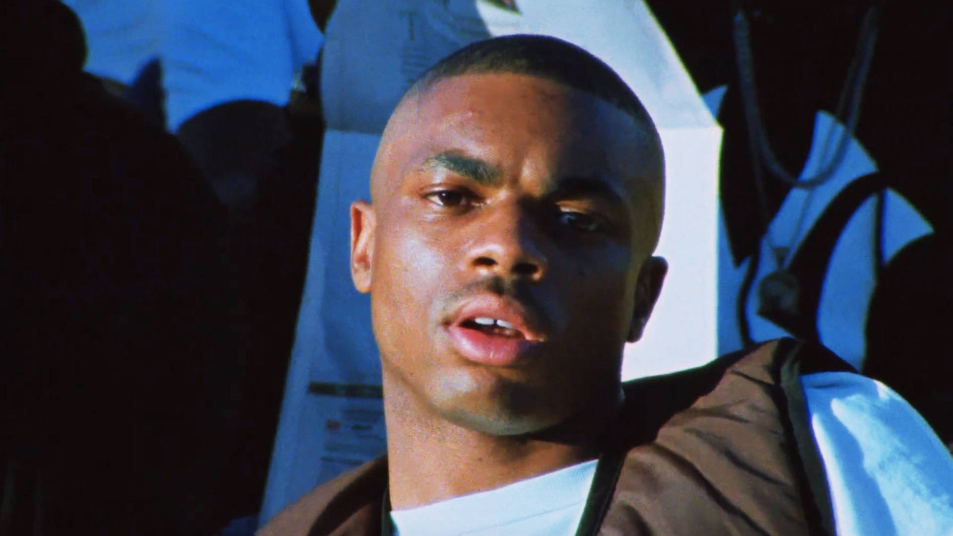 汗濕 Vince Staples 壁紙 — 一位年輕黑人男子在戲劇性的藍色燈光下，表情嚴肅的特寫。