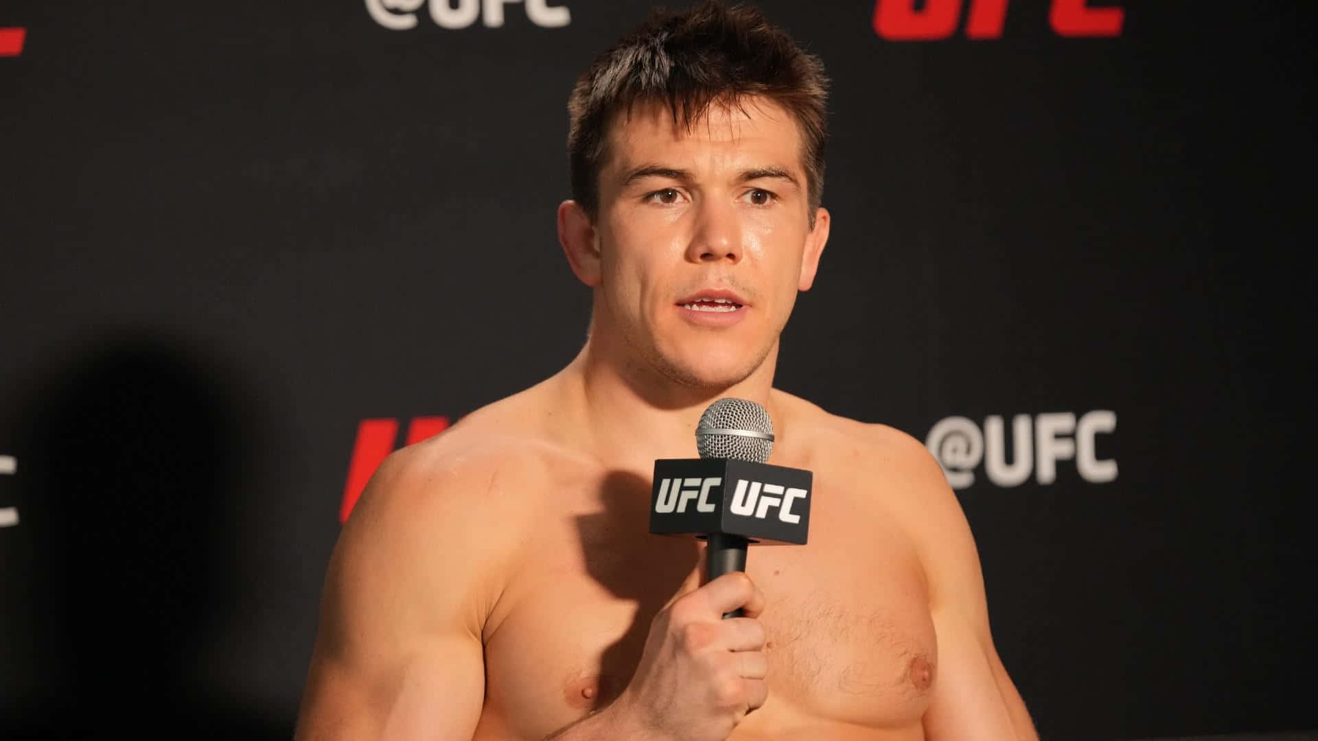 赤裸上身的UFC拳手在記者會上對著咪高峰說話。