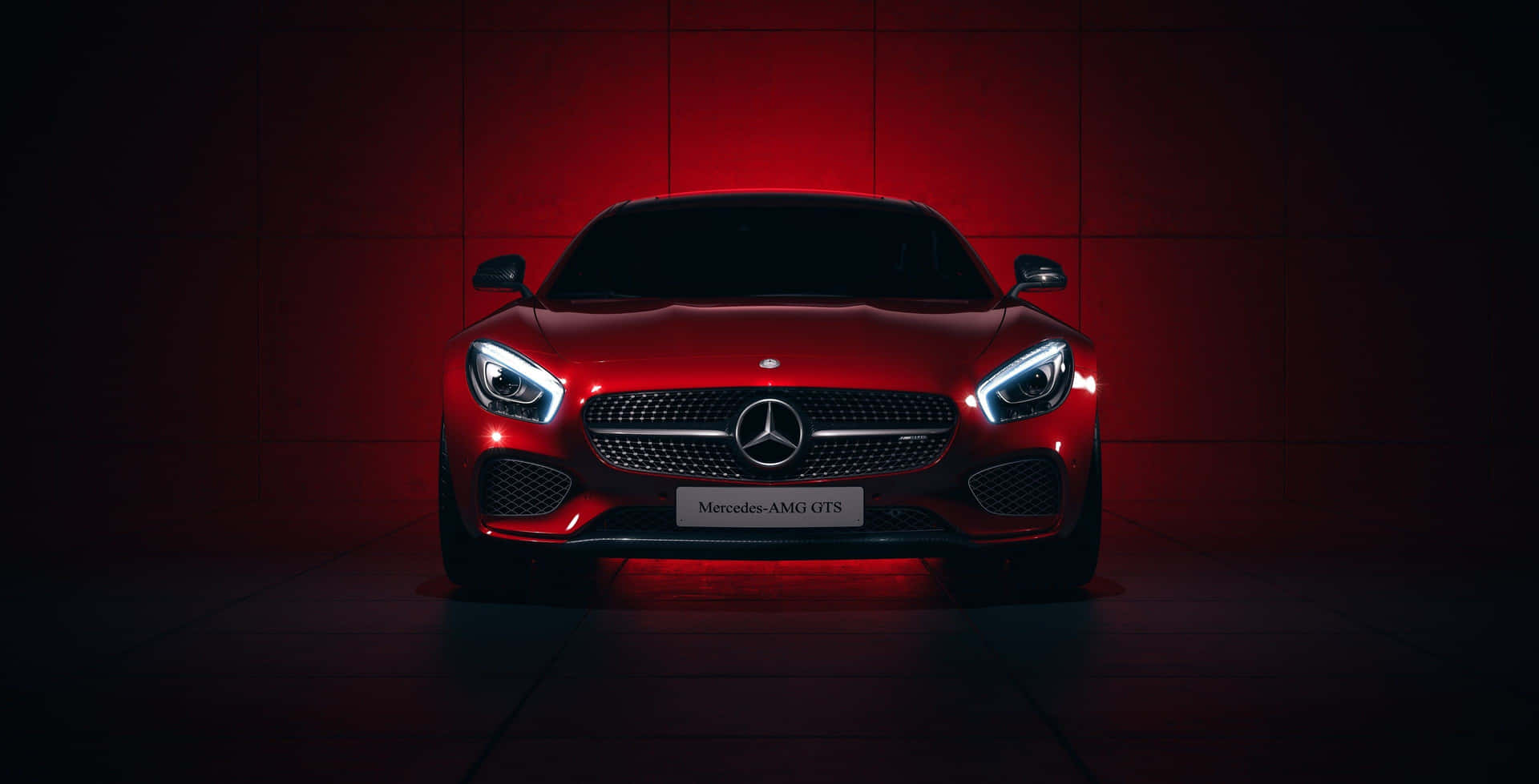 紅色 Mercedes-AMG GTS 跑車在黑暗的攝影棚中以紅色燈光照亮。