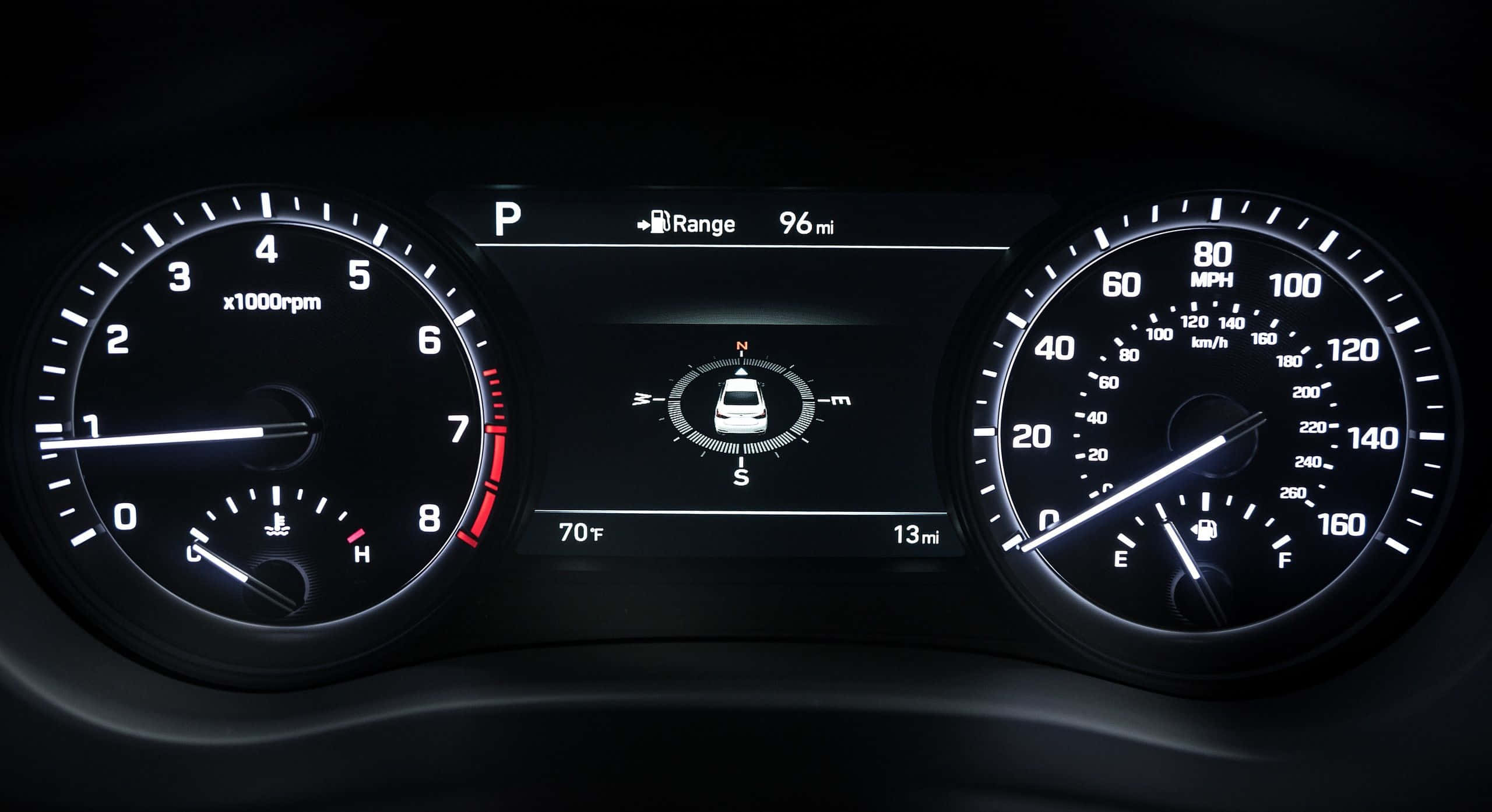 Genesis G80 桌布 壁紙 — 汽車發光儀表板的特寫，顯示速度計、轉速計和數位顯示屏，並帶有泊車檔和續航里程指示器。