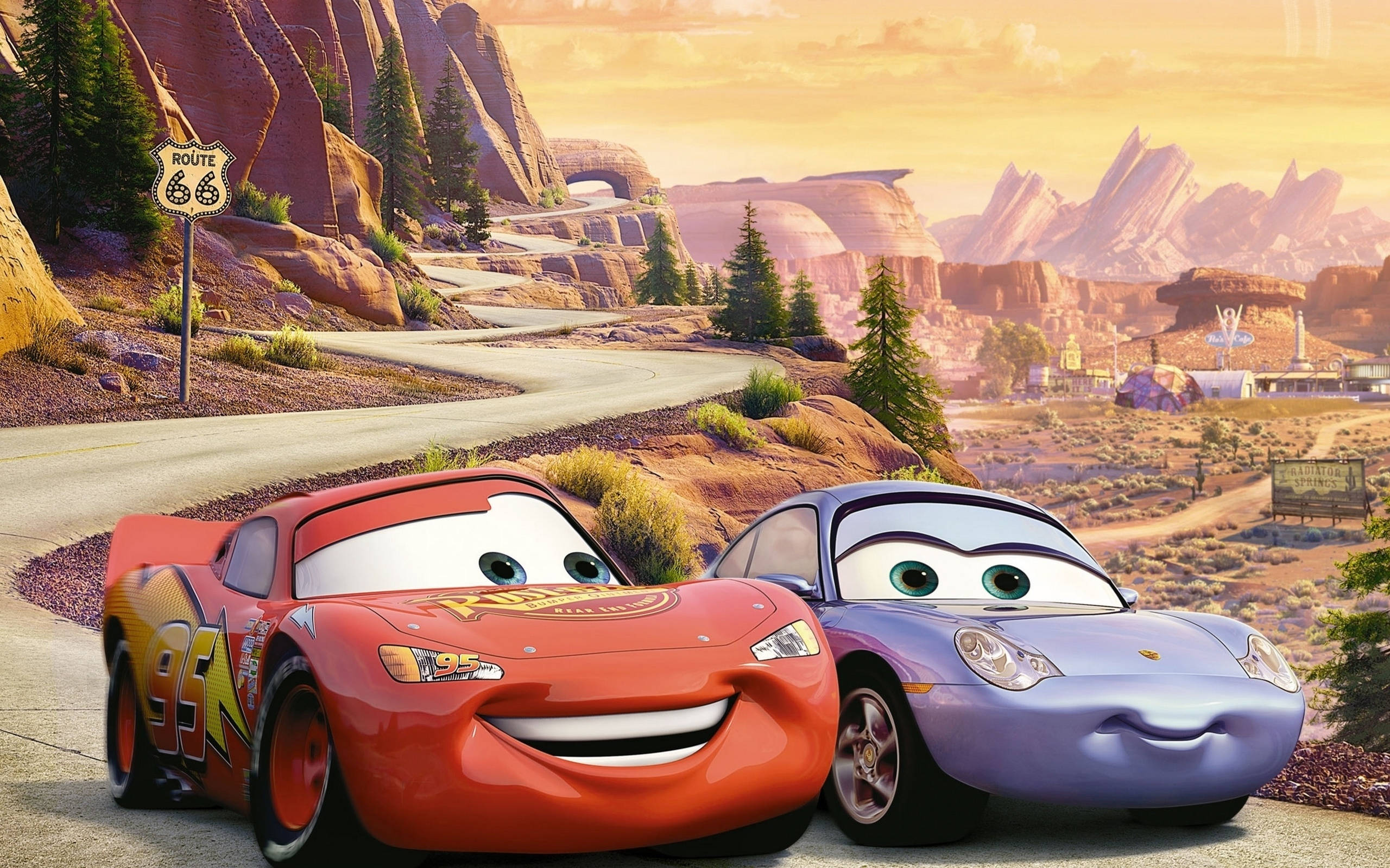 汽車總動員：Lightning McQueen 與 Rainie 並駕齊驅 壁紙 — 兩輛動畫車閃電麥坤和莎莉卡蕾拉在金色夕陽天空下的沙漠公路上微笑。