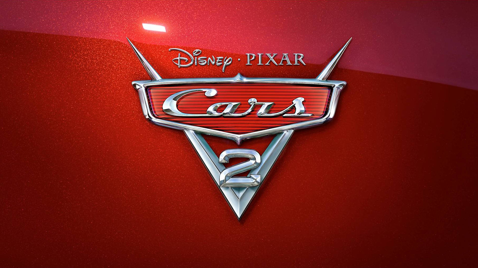 《汽車總動員》中的閃電麥昆領跑賽道 壁紙 — 閃亮的鍍鉻Cars 2標誌在攝影棚燈光下，在帶有紋理的紅色汽車引擎蓋上閃耀。