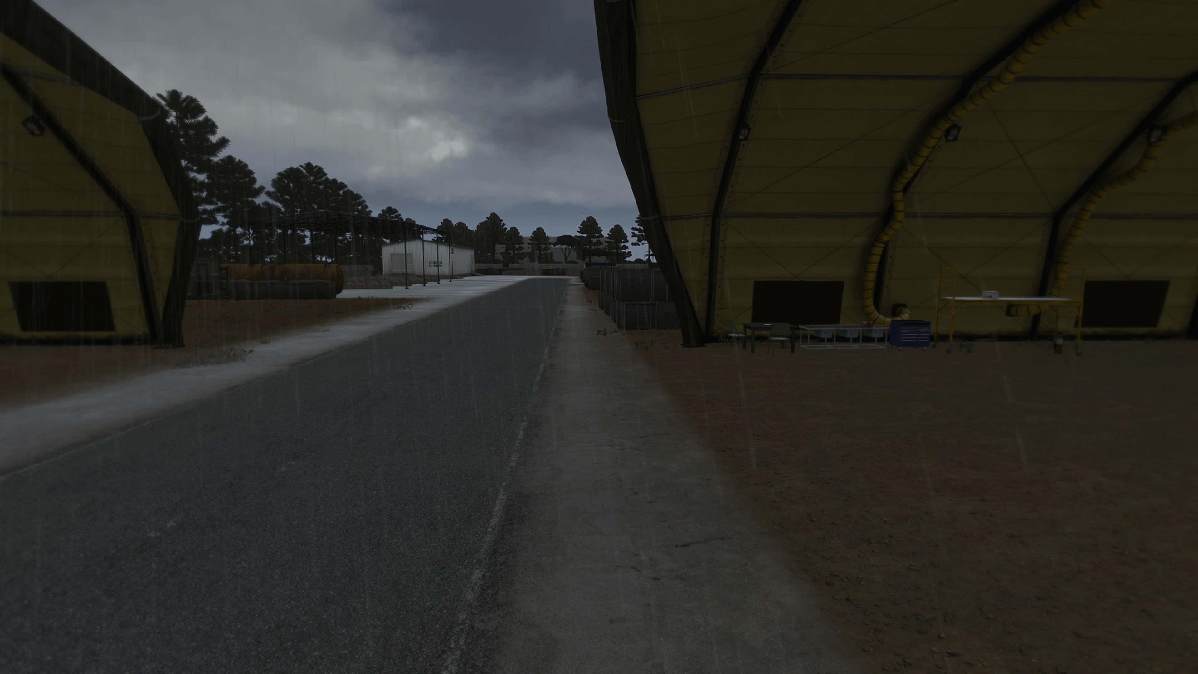 沉浸式 4K DayZ Epoch Mod 遊戲背景 壁紙 — 在陰沉多雲的天空下，兩座大型黃色機庫之間一條被雨水打濕的小路，遠處有樹木。