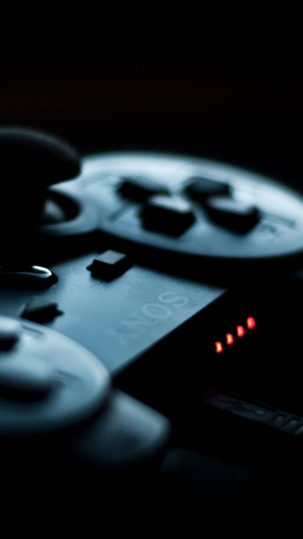 沉浸式 iPhone 遊戲體驗搭配 DualShock 控制器 壁紙 — Sony PlayStation 控制器在黑暗背景中發出紅光的特寫。