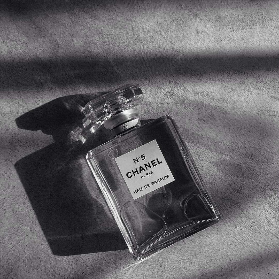 Chanel No 5 香水瓶放在布料上，帶有強烈陰影。