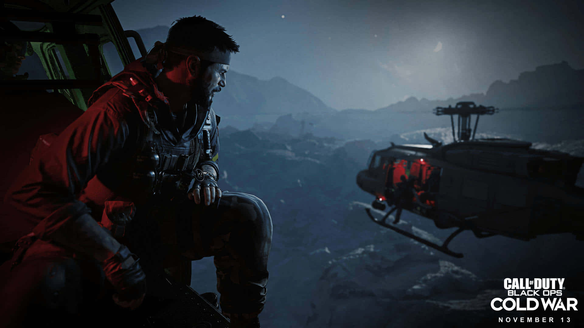 沉浸式遊戲體驗 - 《決勝時刻：黑色行動冷戰》遊戲畫面背景 壁紙 — 一名身穿戰術裝備的士兵在夜間坐在直升機內，俯瞰月光下白雪皚皚的山地地形。