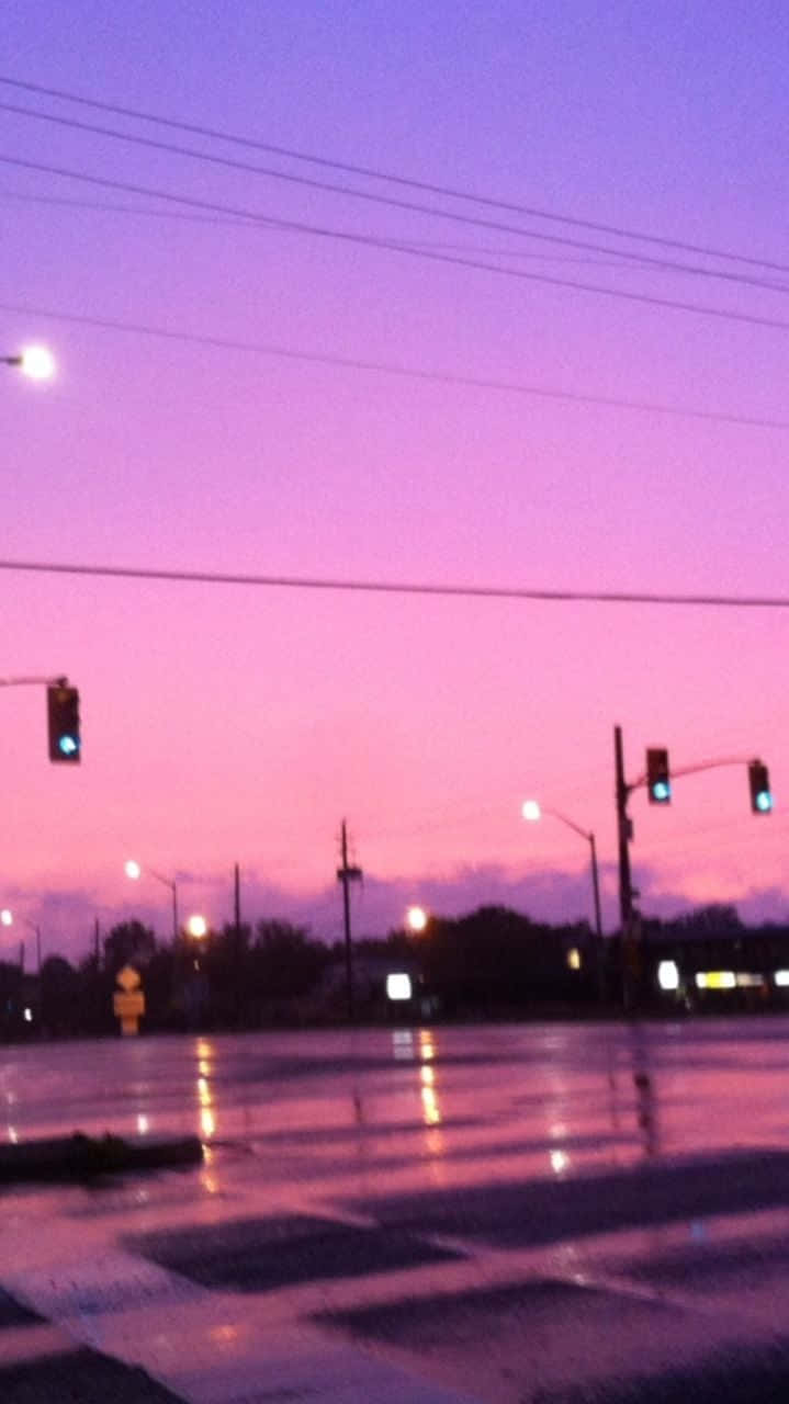 黃昏時下雨的城市街道，閃爍的交通燈和紫色天空。