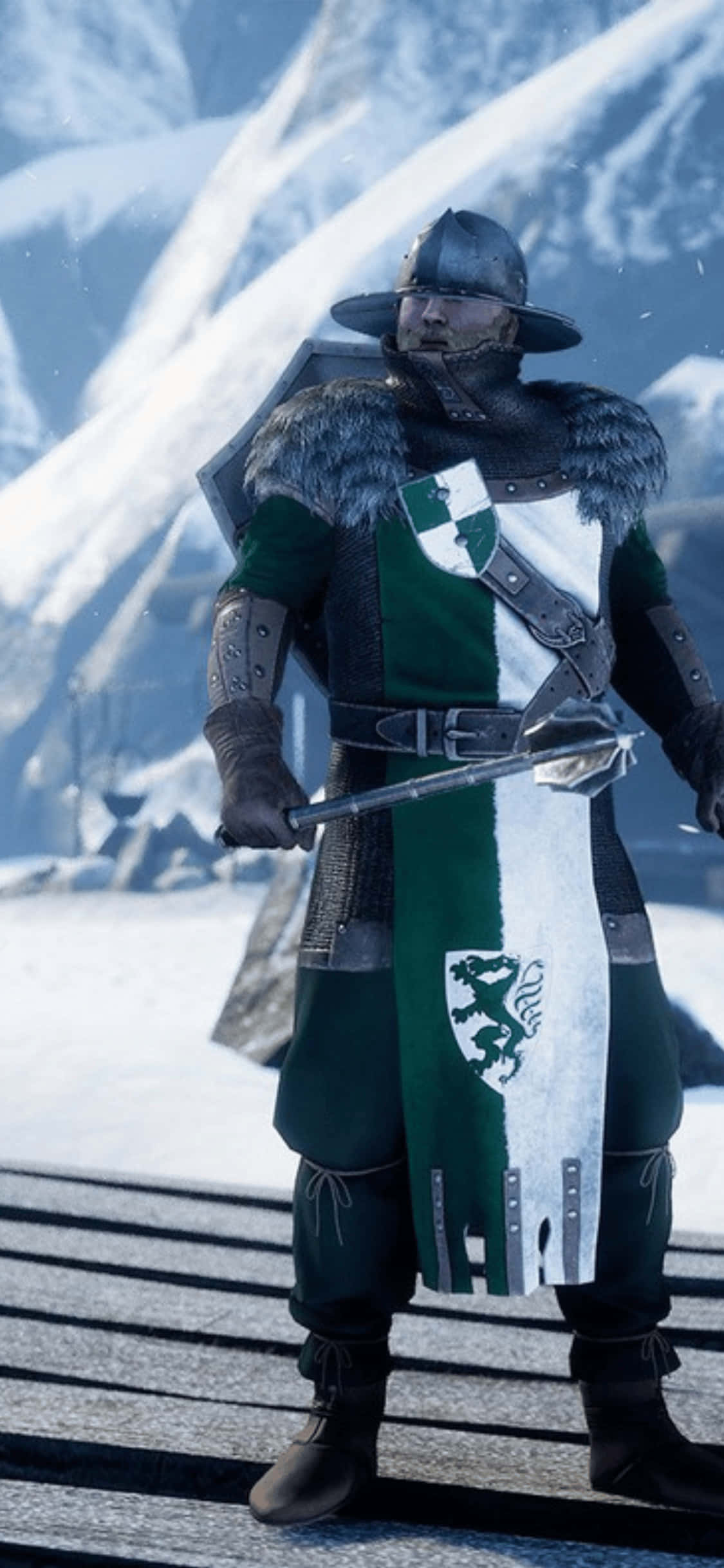 沉浸於 Mordhau 世界 — iPhone XS 壁紙 — 一位身穿綠色和白色紋章鎧甲的騎士，在白雪覆蓋的山口上堅定地站著，手持劍和盾牌。