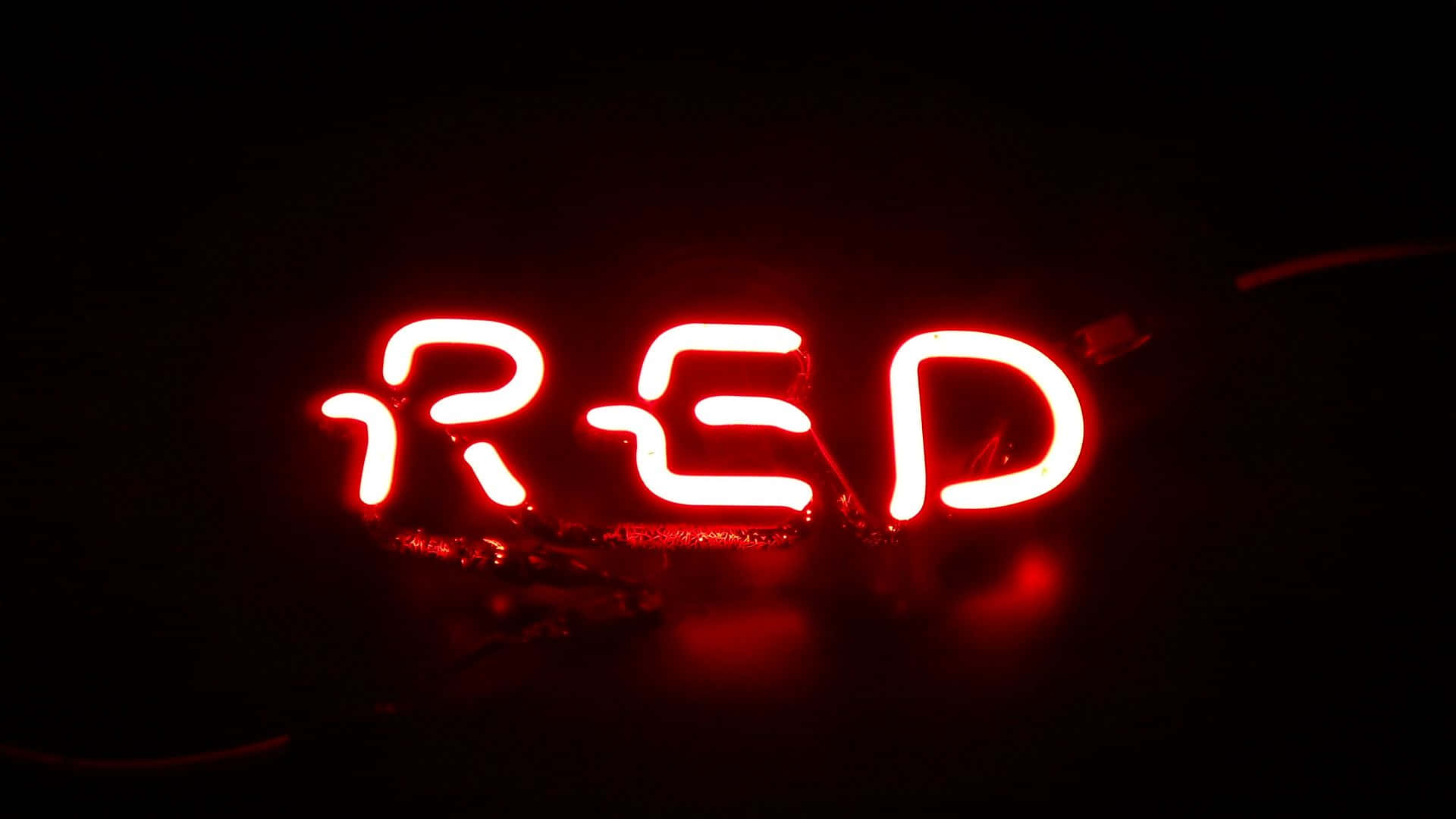 在黑暗的房間中，一個發光的紅色霓虹燈牌拼寫著RED。