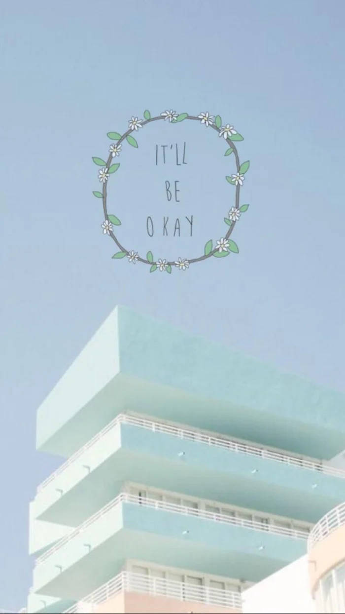 粉藍色建築物，帶有花環圖案，上面寫著「It'll be okay」，背景是晴朗天空。