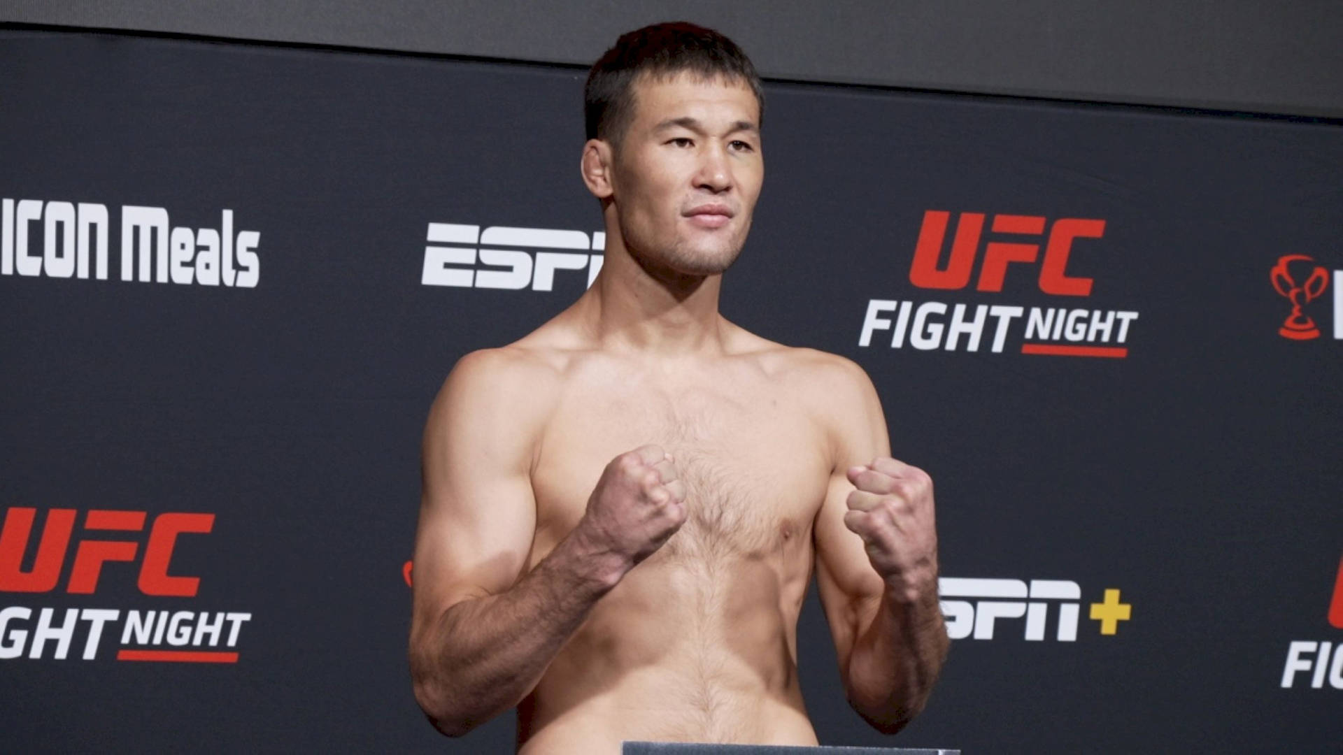 UFC拳手在稱重活動中赤裸上身，拳頭高舉擺姿勢。