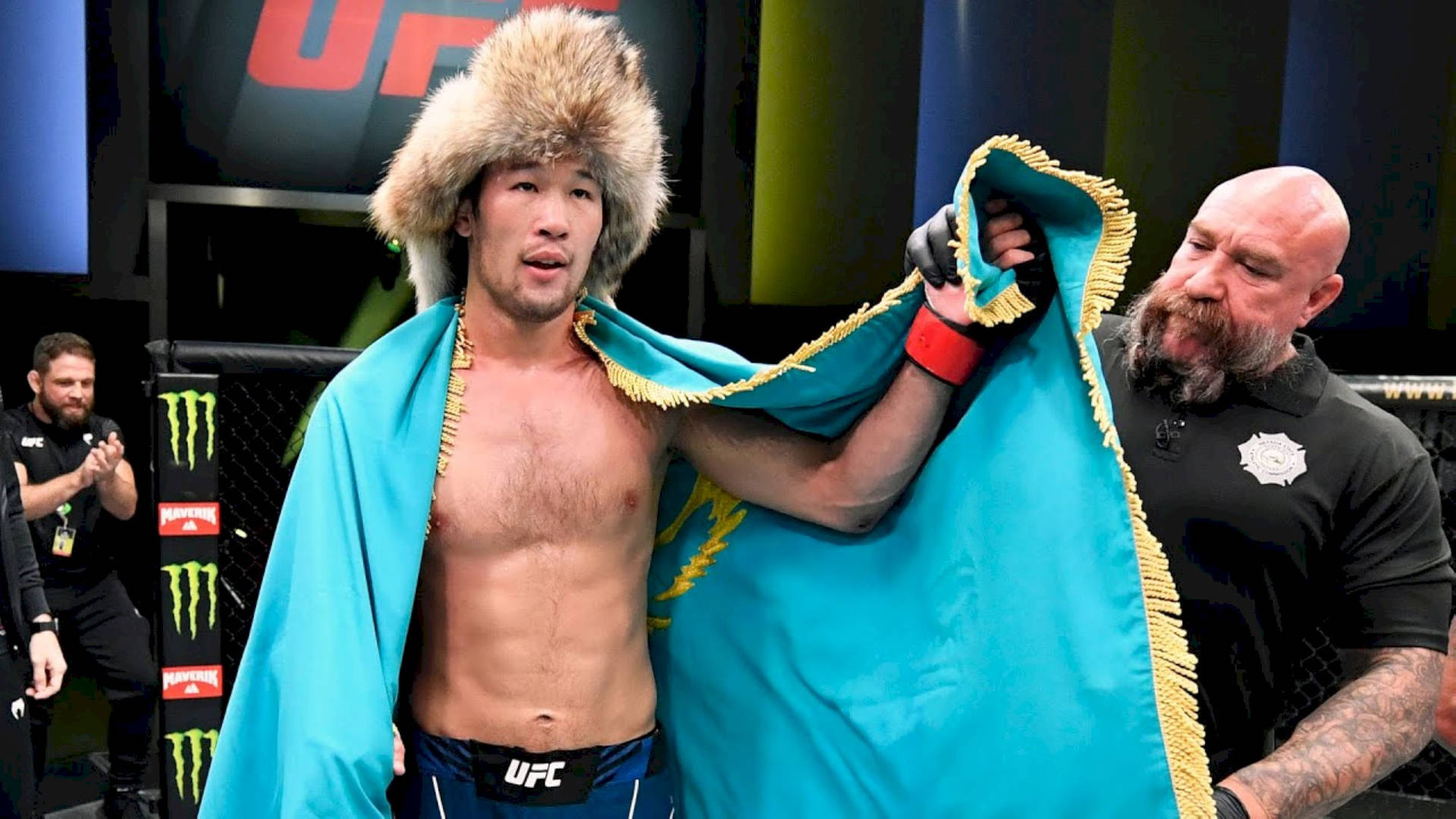 UFC拳手在八角籠中獲勝後披著國旗戴著毛帽。