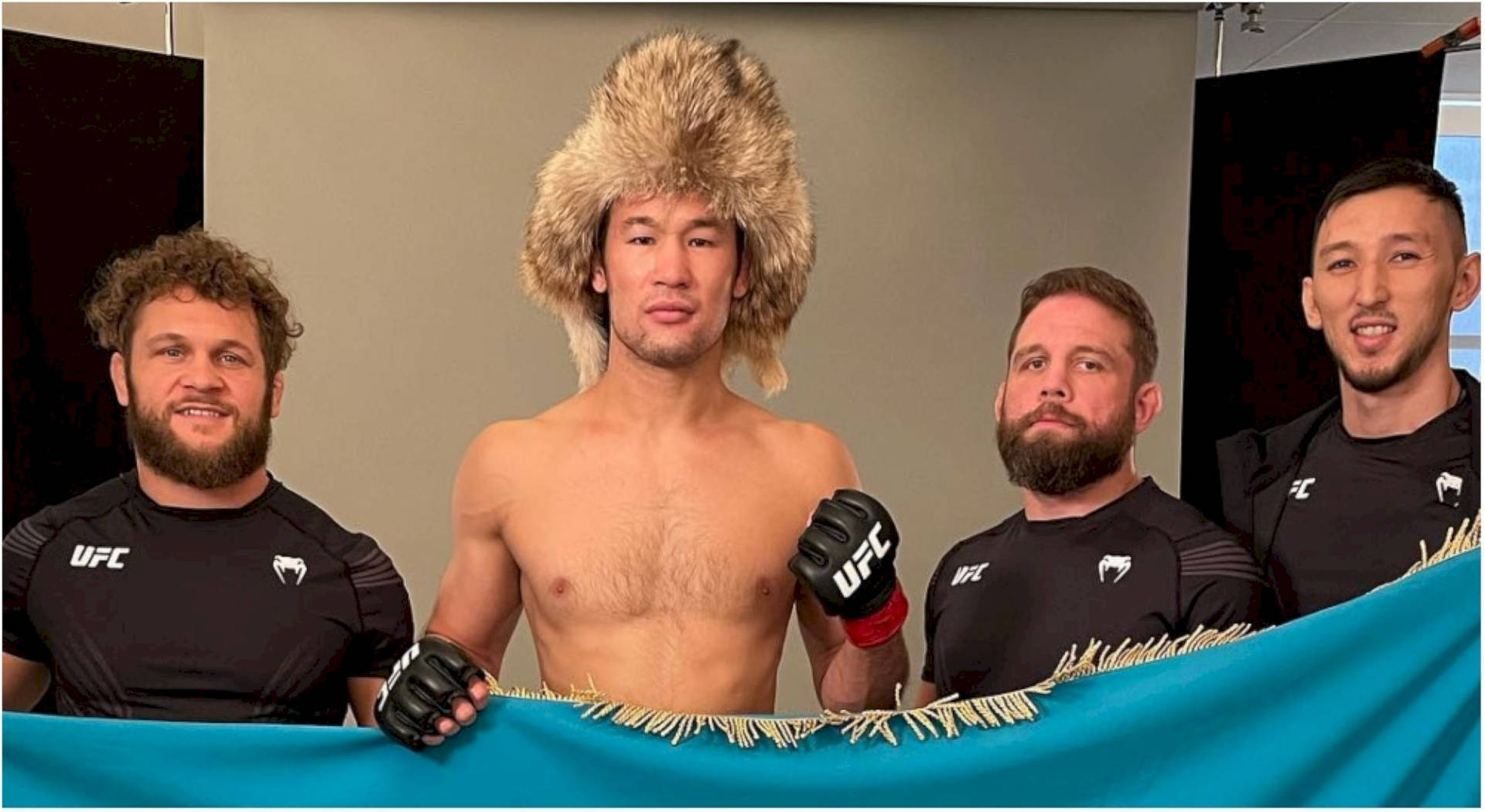 四名UFC戰士與一面藍旗合影，其中一人戴著大毛帽。