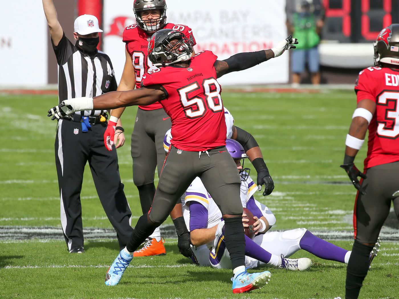 沙奎爾·巴雷特 坦帕灣海盜隊 NFL 壁紙 — 坦帕灣海盜隊的線衛身穿紅色58號球衣，在陽光明媚的足球場上慶祝一次擒抱，附近有裁判和其他球員。