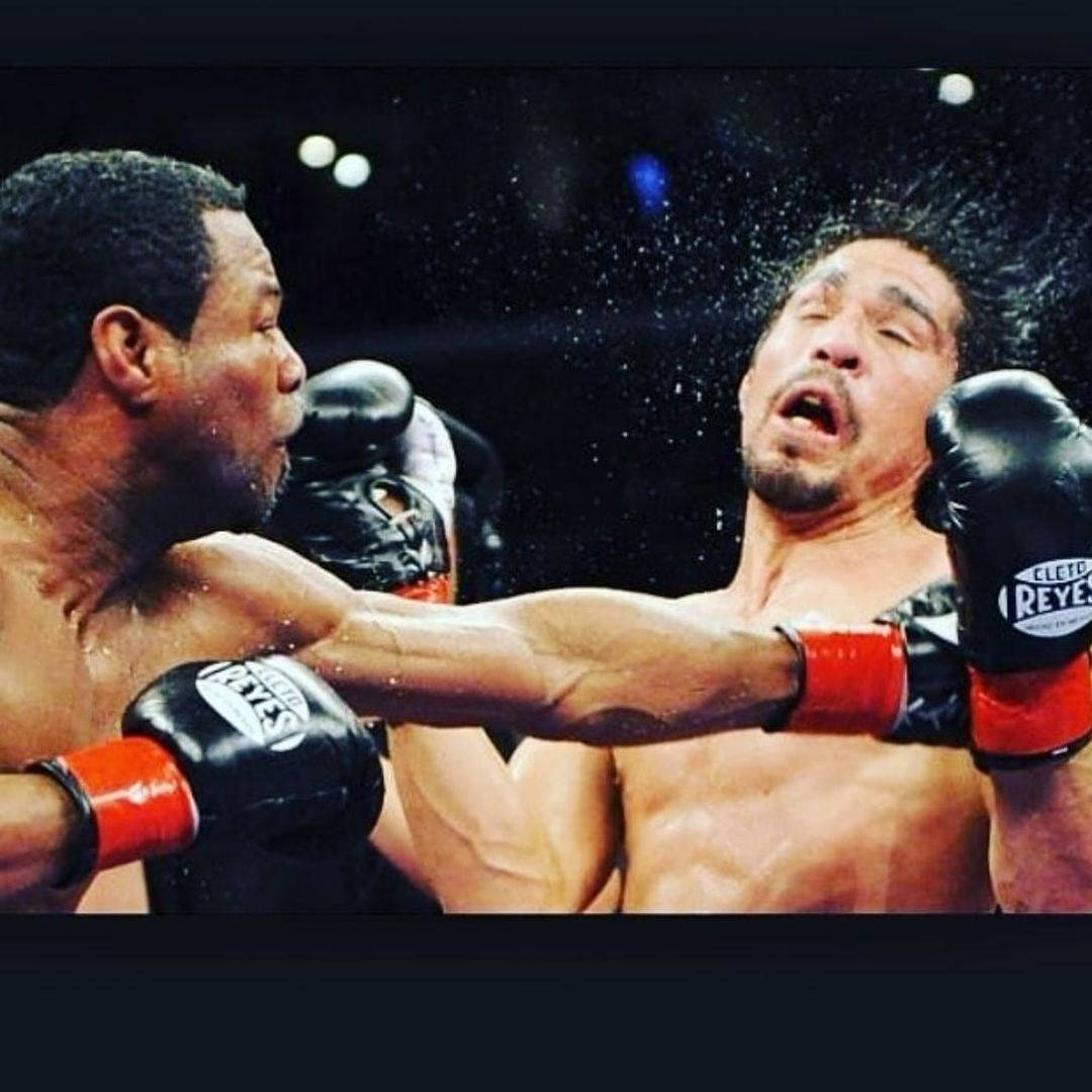 沙恩·莫斯利出拳 壁紙 — 一名拳擊手在明亮的場館燈光下，於被雨水濺濕的擂台上向對手打出強力一拳。
