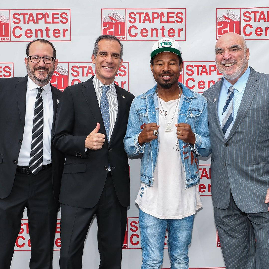 沙恩·莫斯利於紅毯上 壁紙 — 四名男子在Staples Center 20週年活動中愉快地擺姿勢，背景帶有品牌標誌。