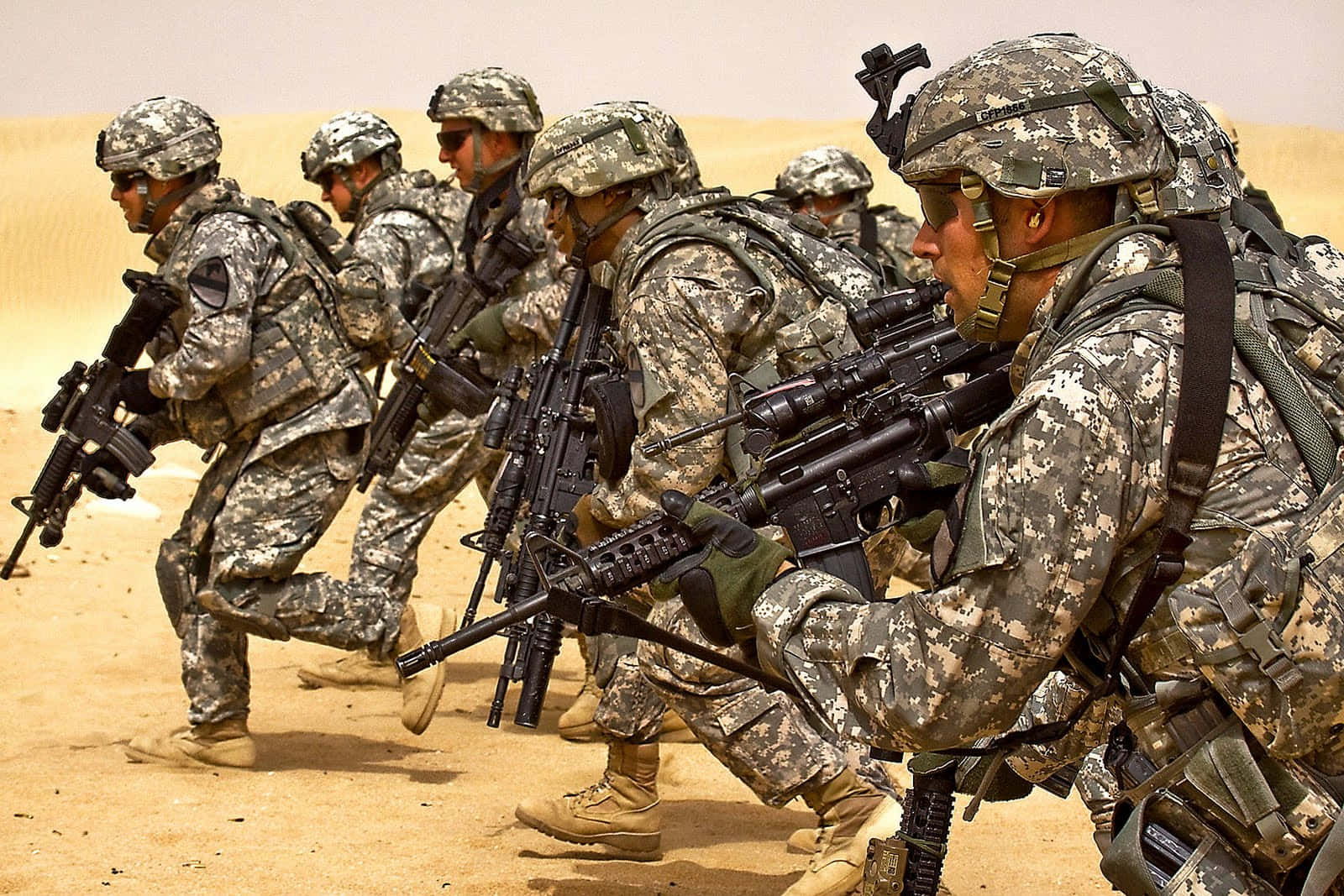 一排身穿沙漠迷彩的士兵持步槍前進。