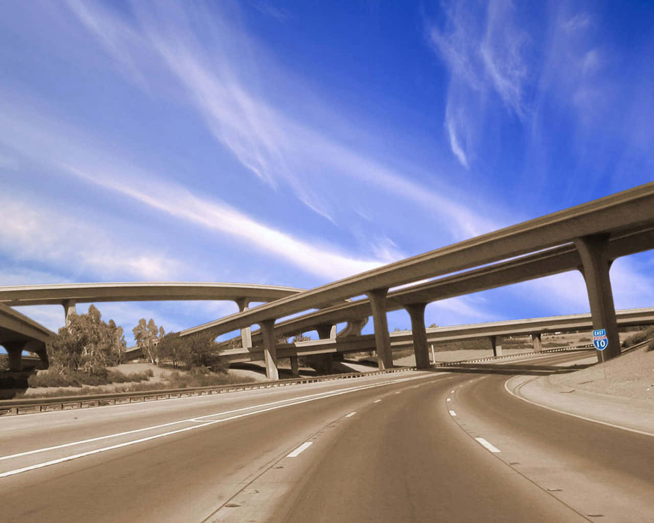 沙漠中的公路段 壁紙 — 在充滿活力的藍天白雲下，一個複雜的混凝土高速公路交匯處的廣闊景觀。