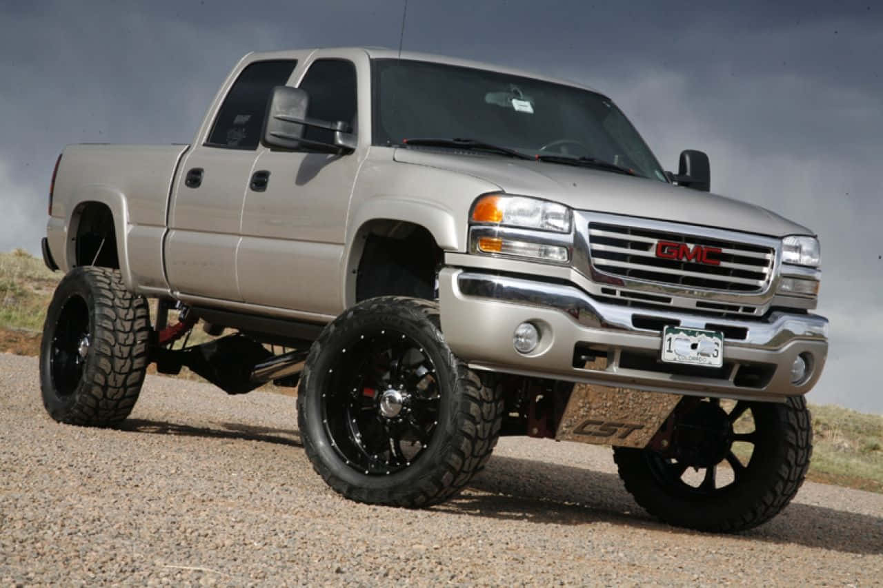 升高嘅銀色 GMC Sierra  pickup 貨車，黑色車輪，碎石路。