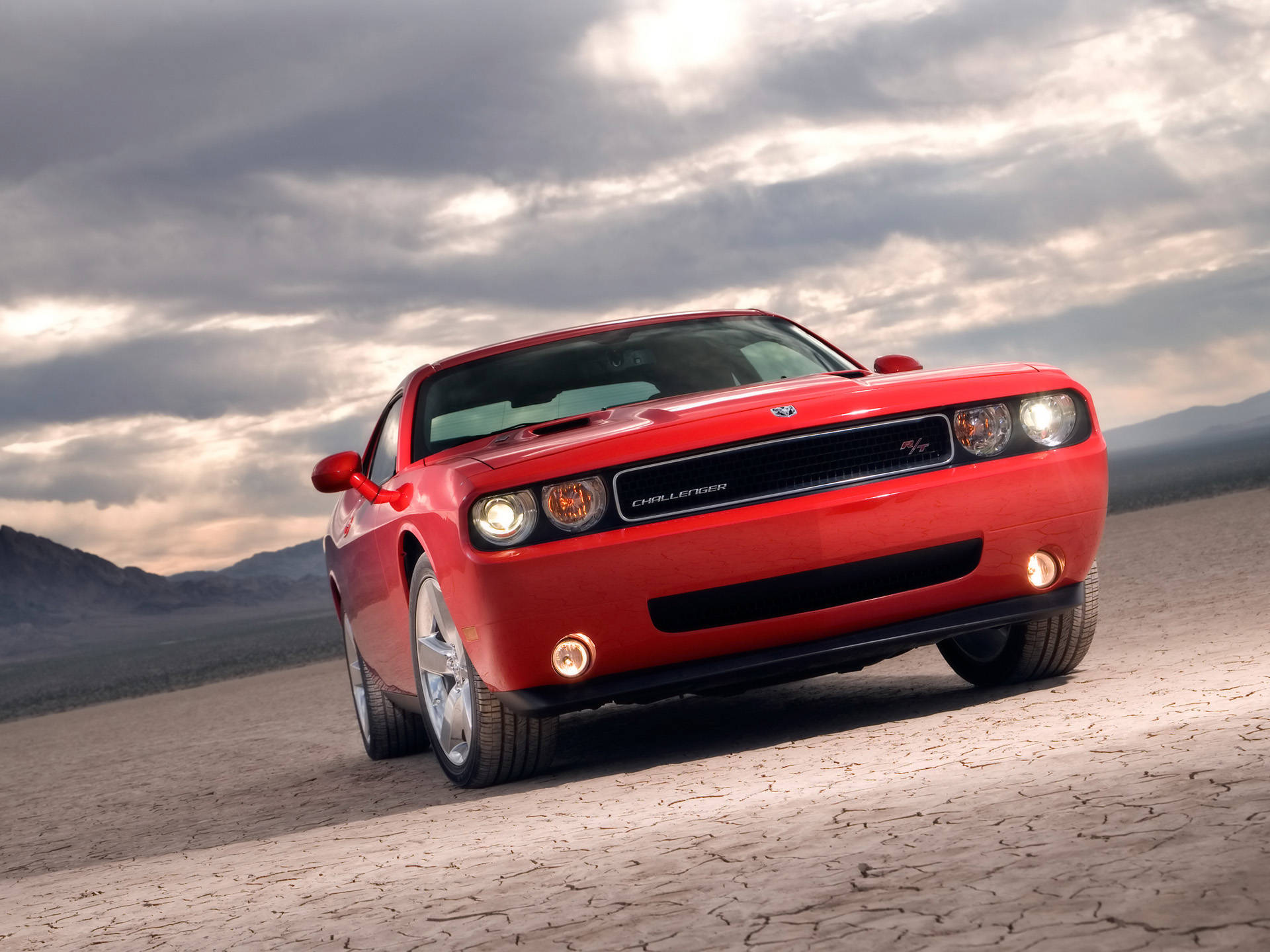 紅色 Dodge Challenger SRT8 停放在龜裂的沙漠地面上，天空多雲。