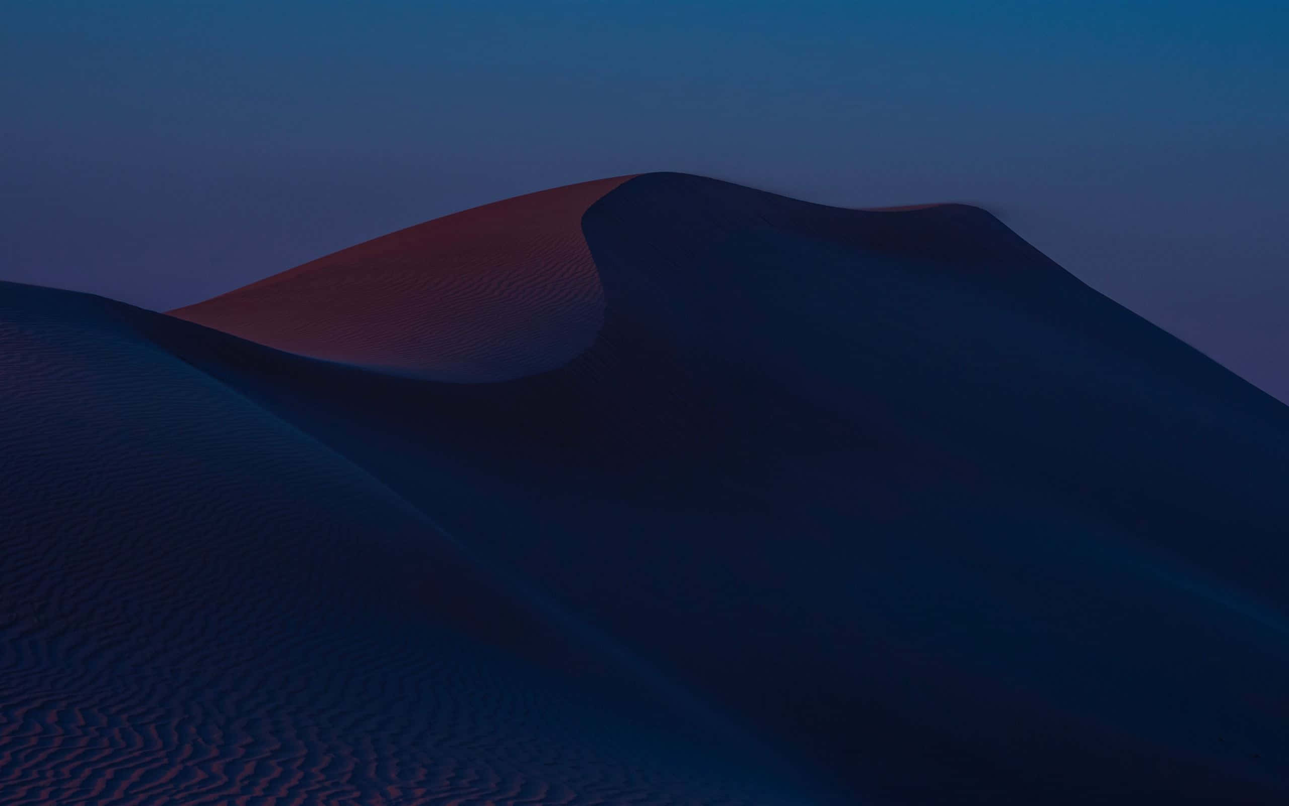 Sand Dunes 桌布 壁紙 — 沙漠沙丘沐浴在暮色中，帶有深藍色陰影和頂部溫暖的紅色光芒。
