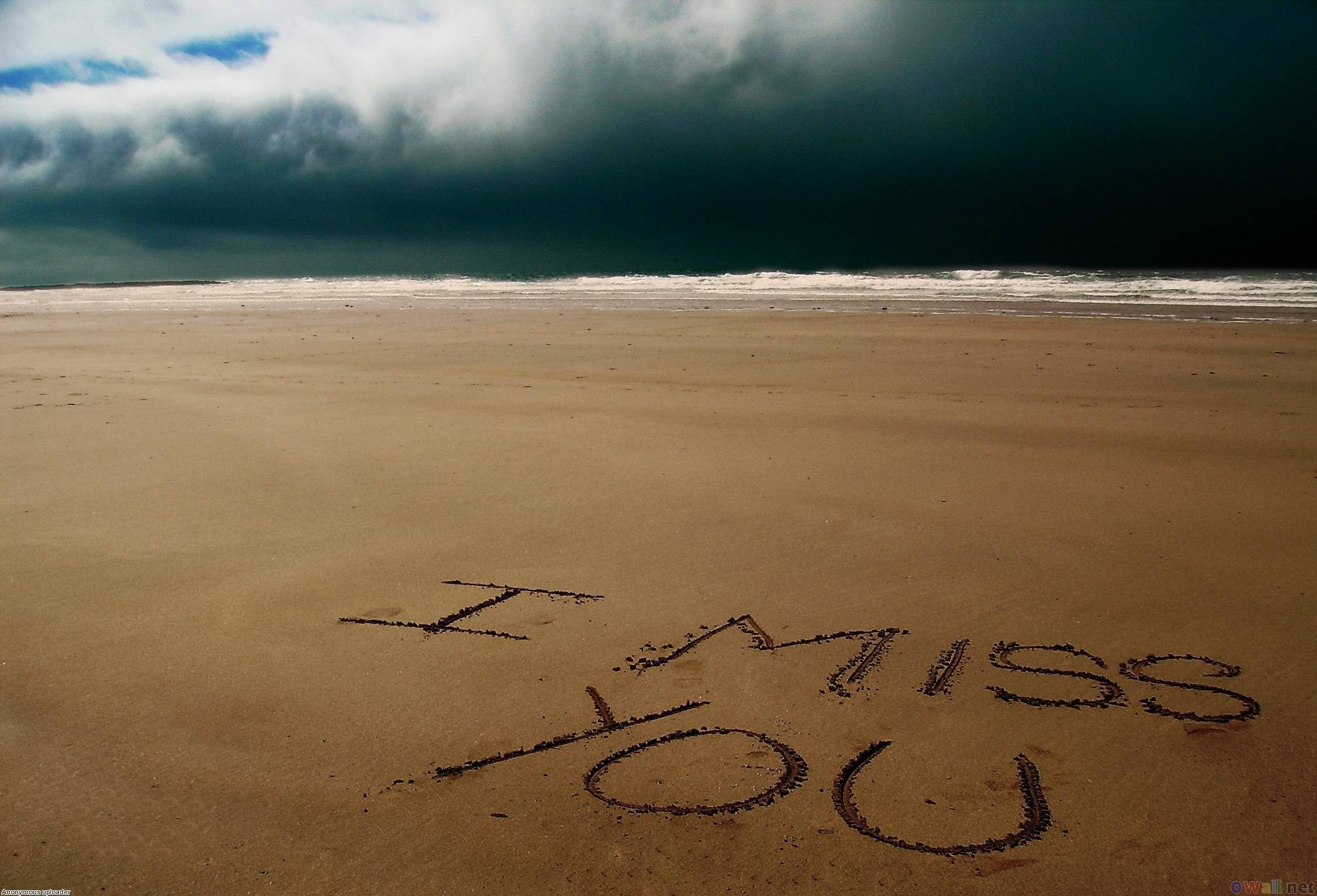 沙灘上的我好想你 壁紙 — 「I MISS YOU」呢幾個字刻喺廣闊沙灘嘅濕沙上，而黑暗嘅暴風雲籠罩住海洋。